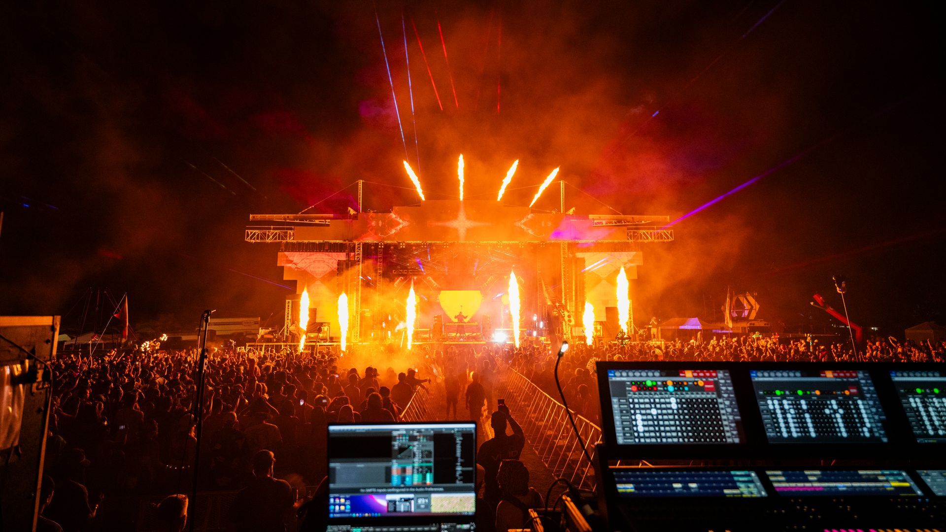 A crowd of people are watching a concert at night.