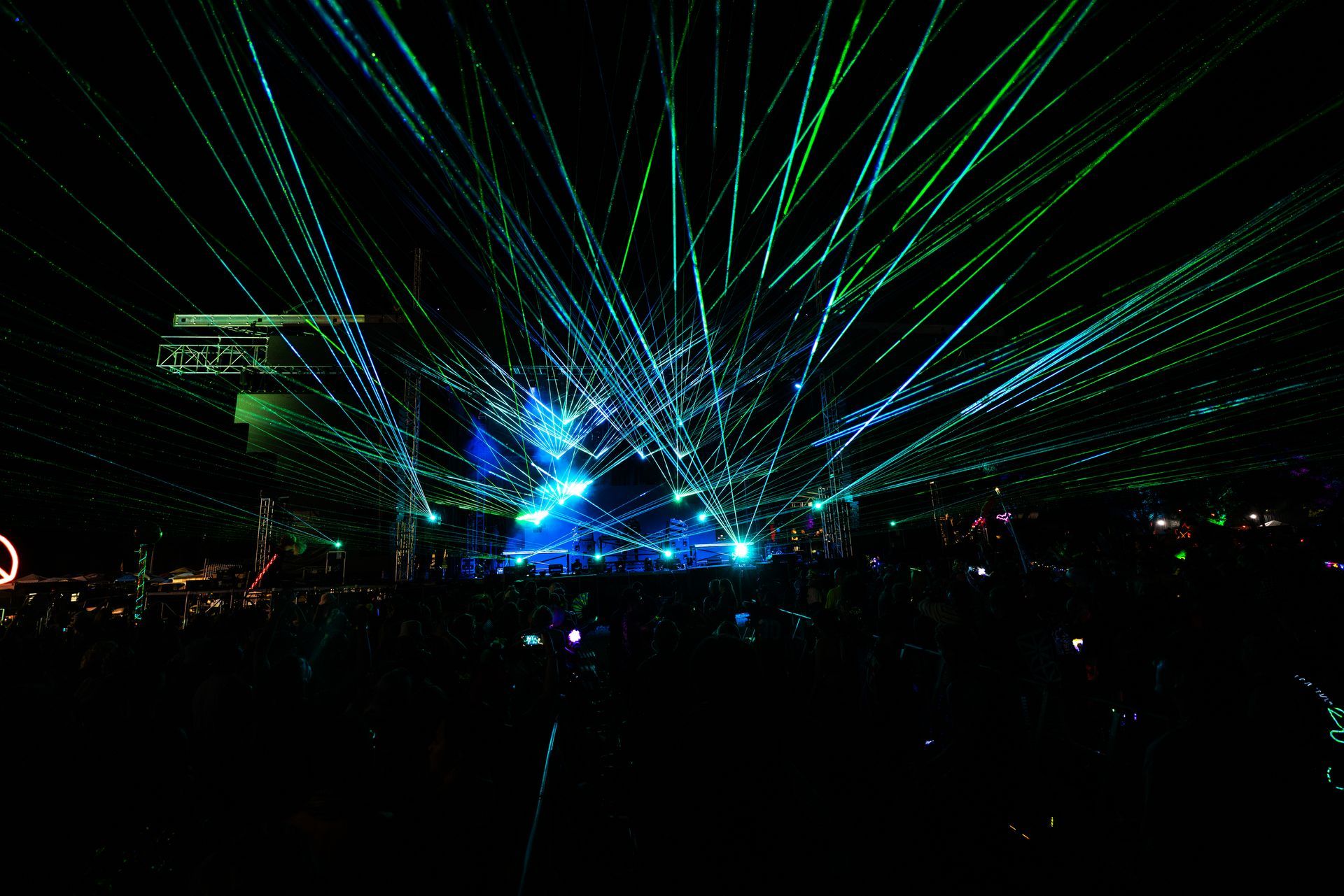 A crowd of people watching a laser show at night
