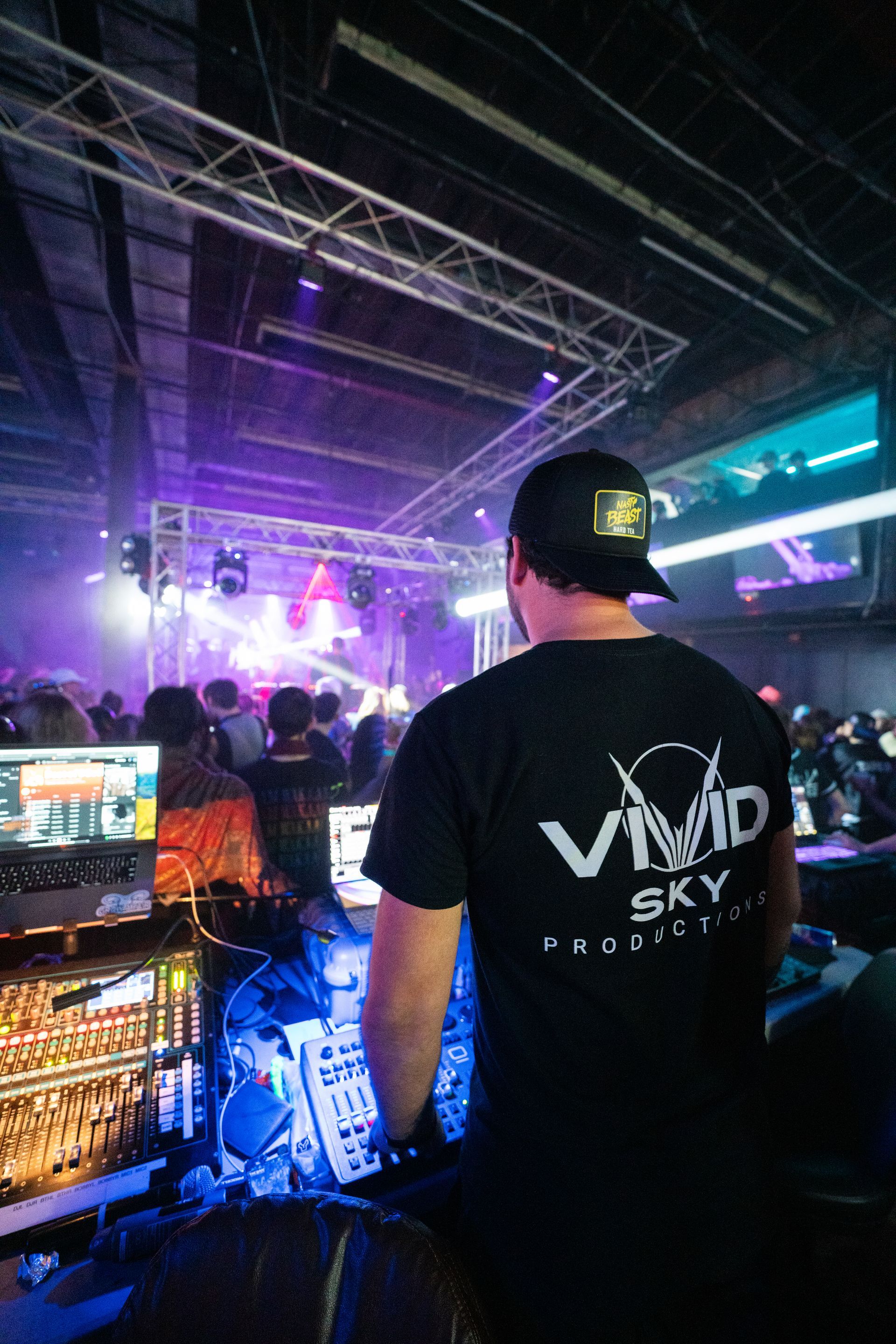 A man is standing in front of a dj booth at a concert.
