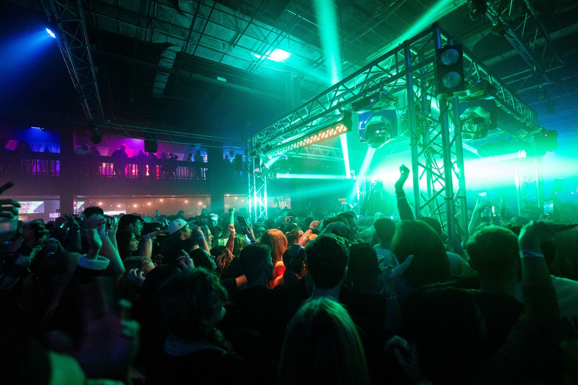 A crowd of people are standing in front of a stage at a concert.