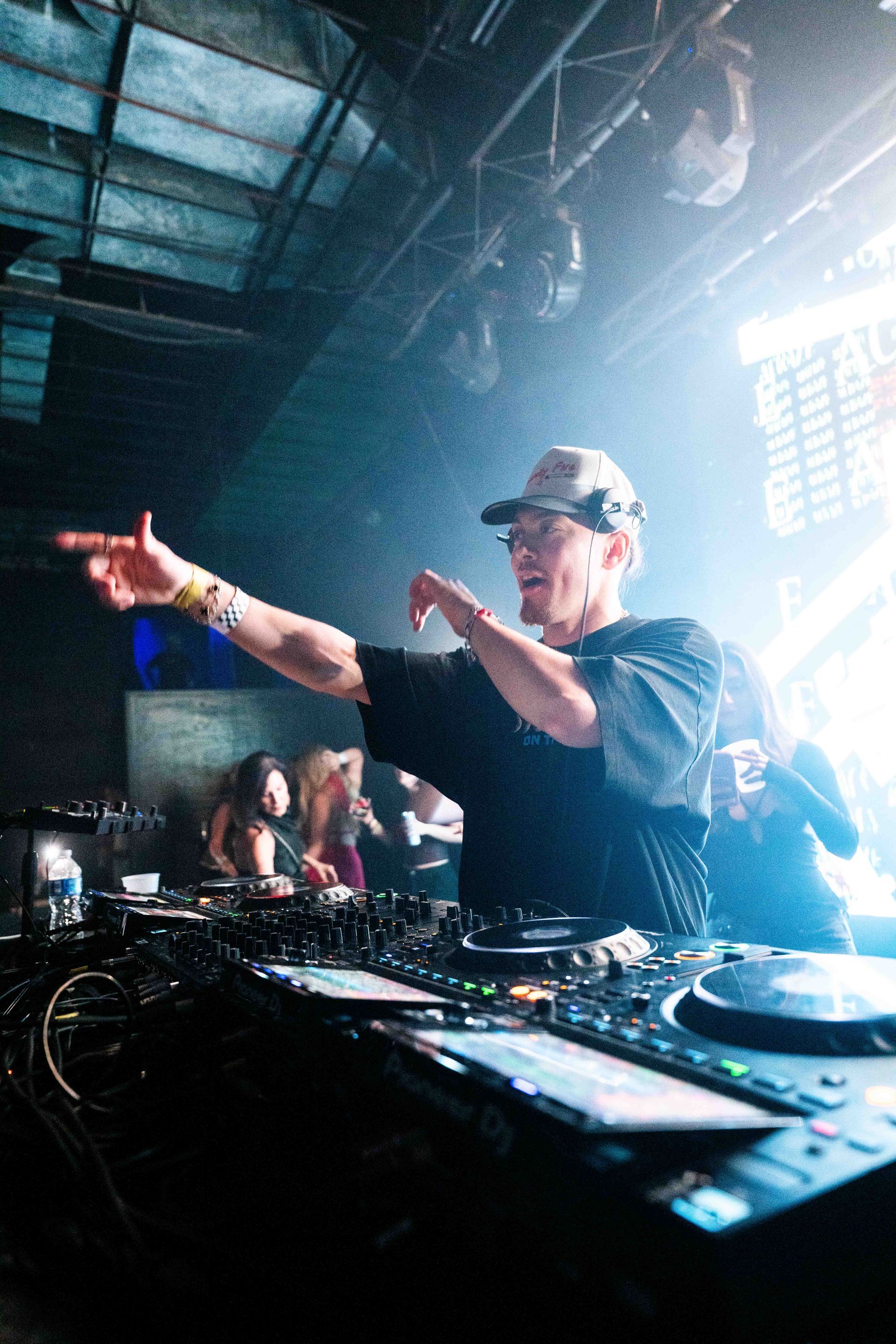 A man is playing a dj set in a dark room.