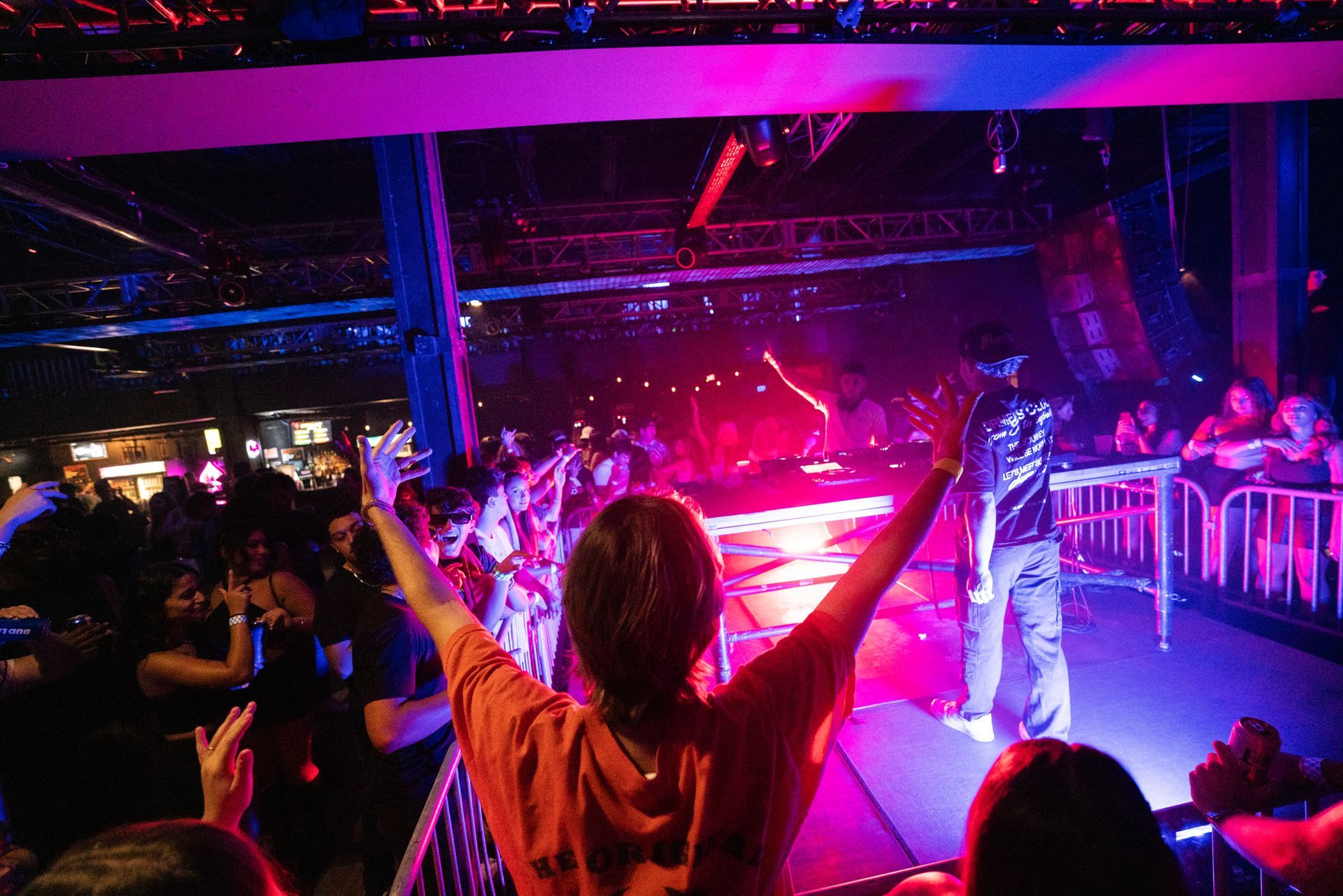 A woman is standing in front of a crowd at a concert with her arms in the air.