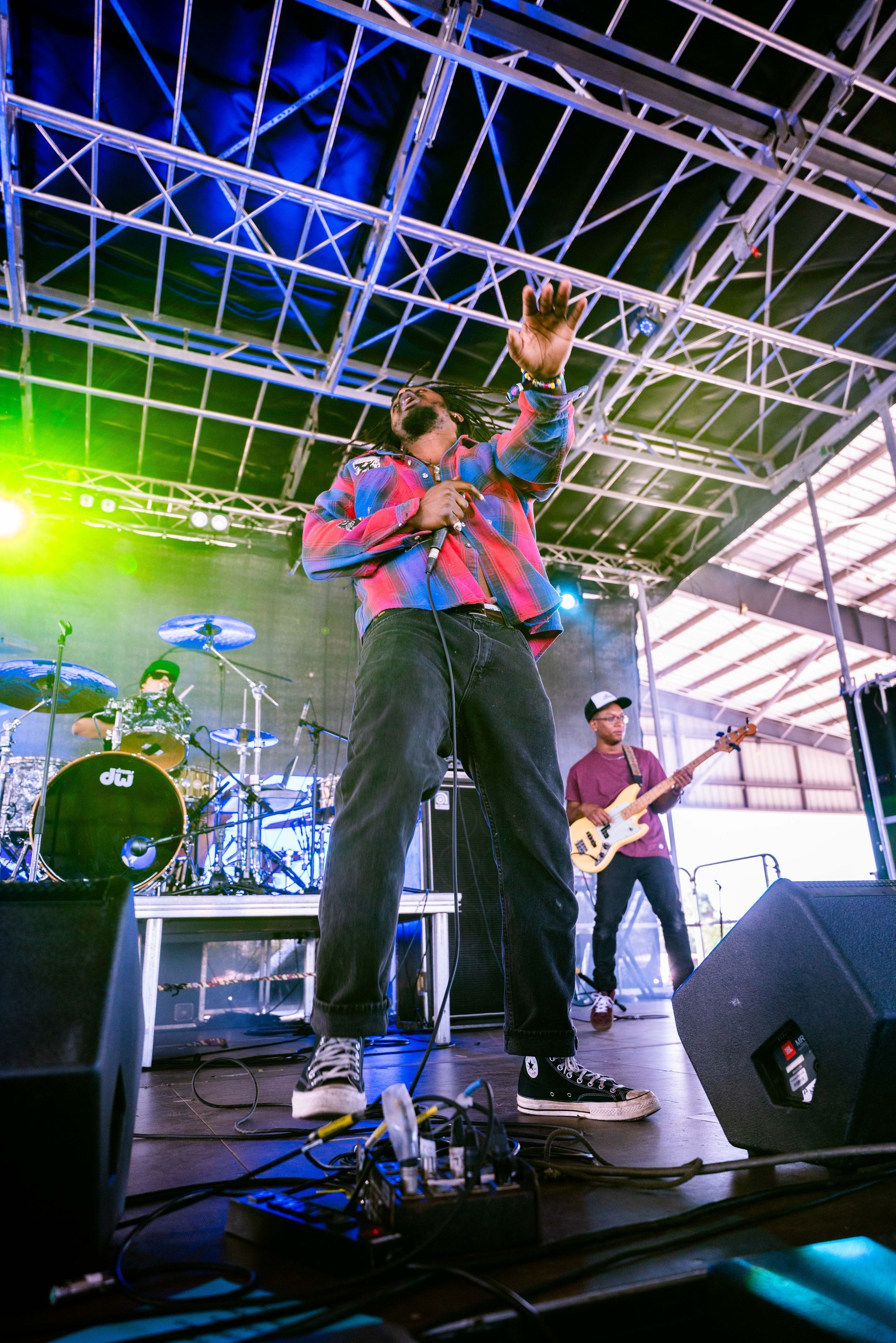 A man is singing into a microphone on a stage with a band behind him.