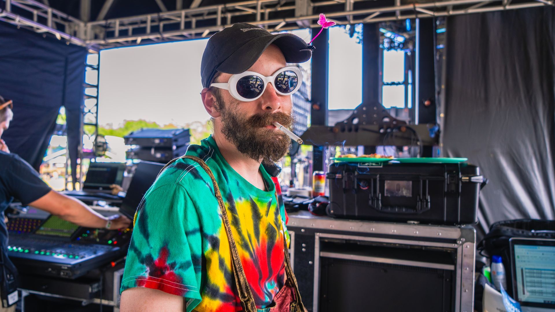A man with a beard is wearing sunglasses and a tie dye shirt.