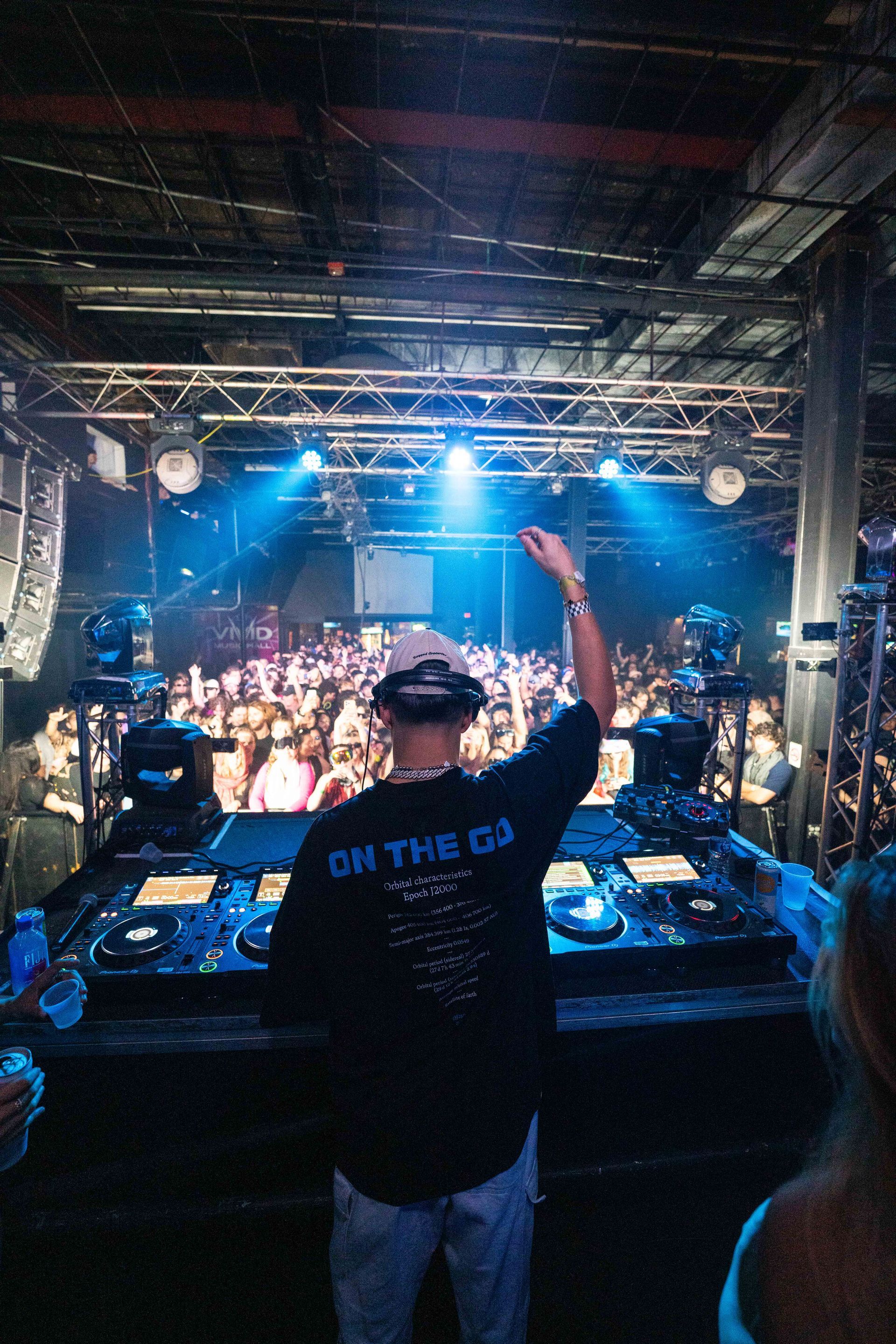 A dj is standing in front of a crowd at a concert.