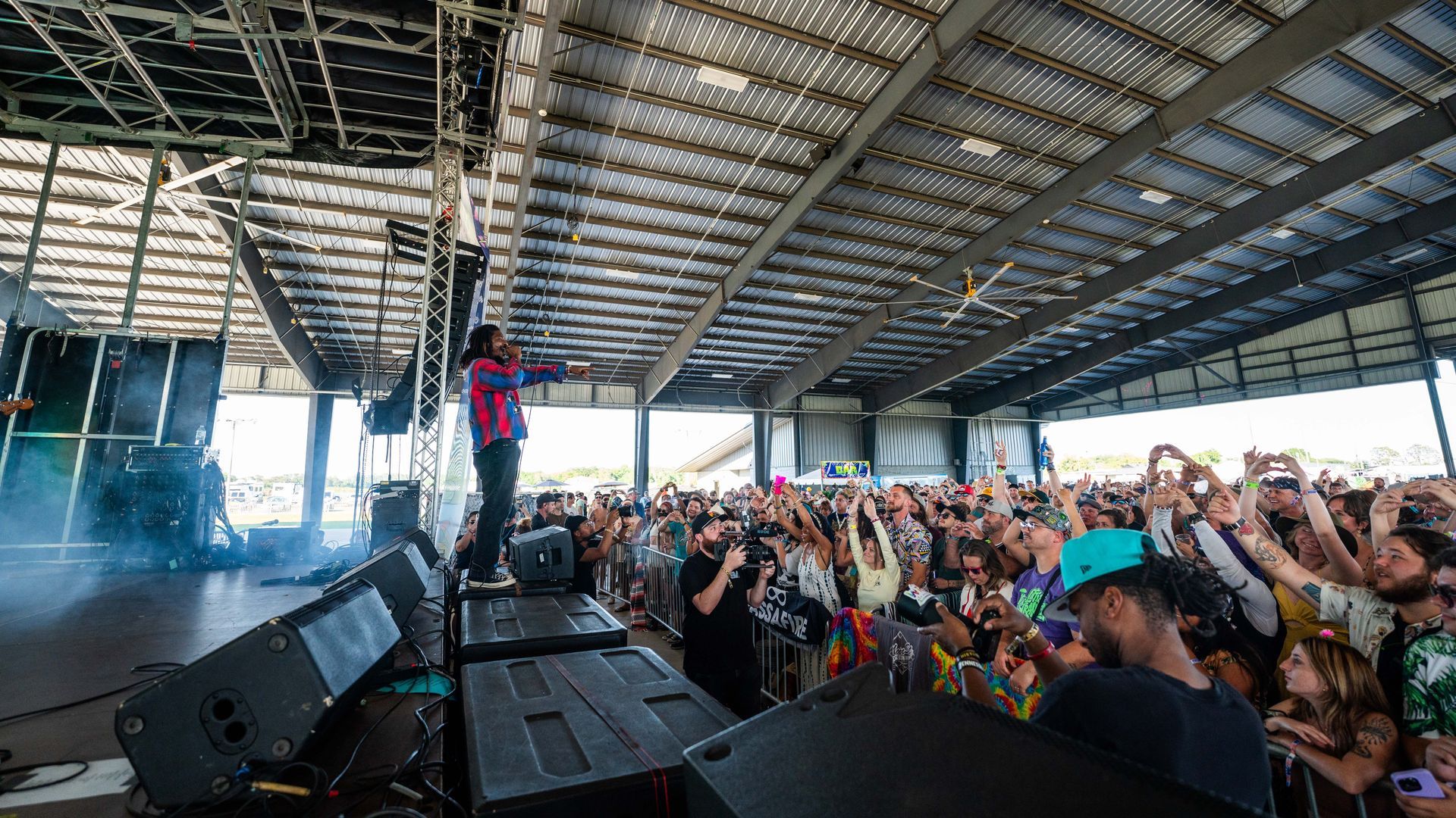 A man is standing on a stage in front of a crowd at a concert.