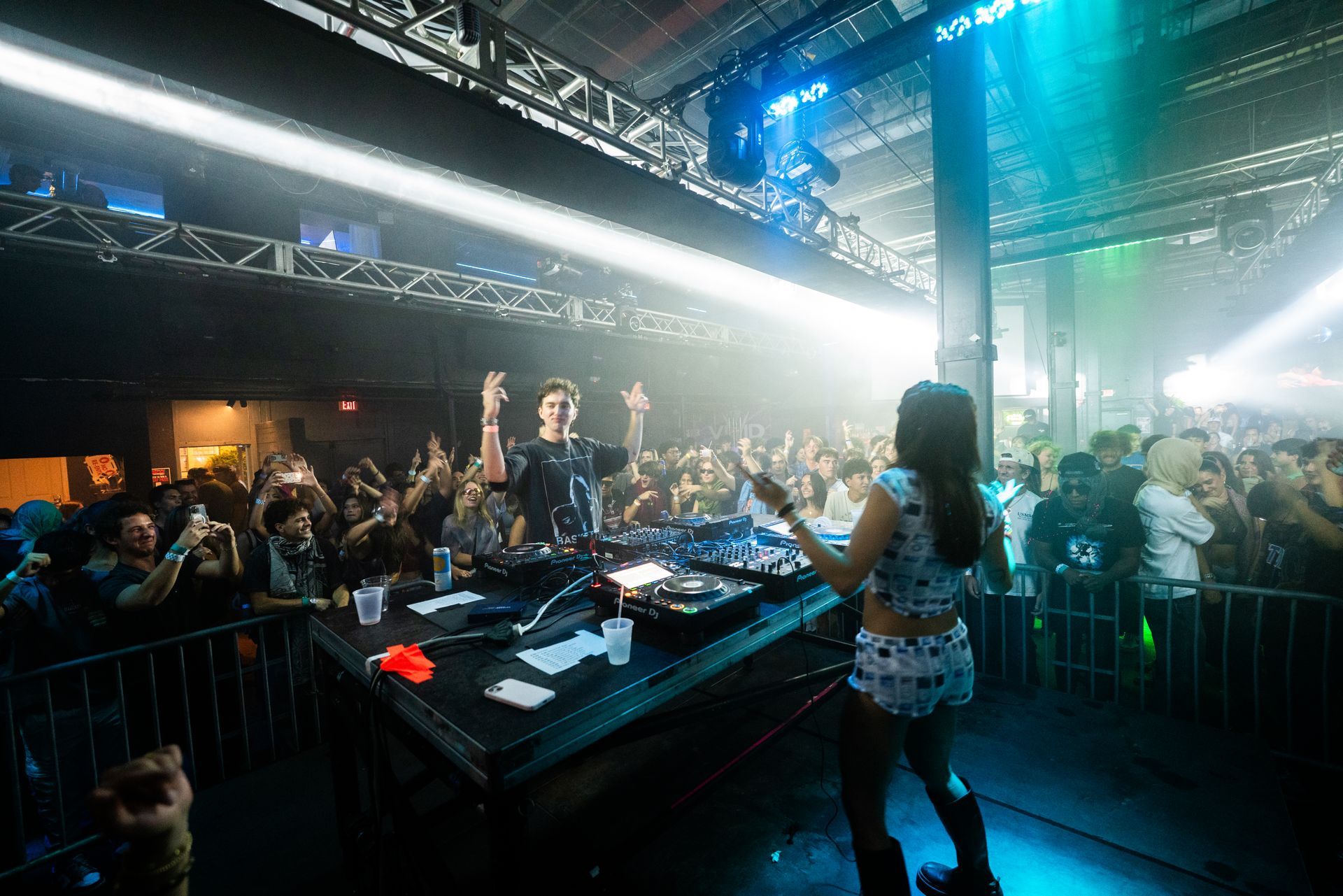A woman is standing in front of a dj at a concert.