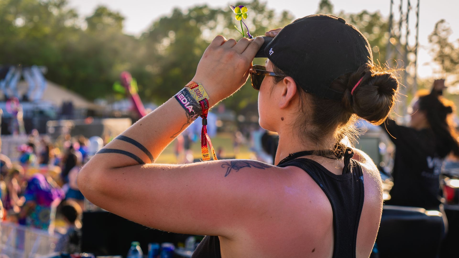 A woman is looking through binoculars at a music festival.