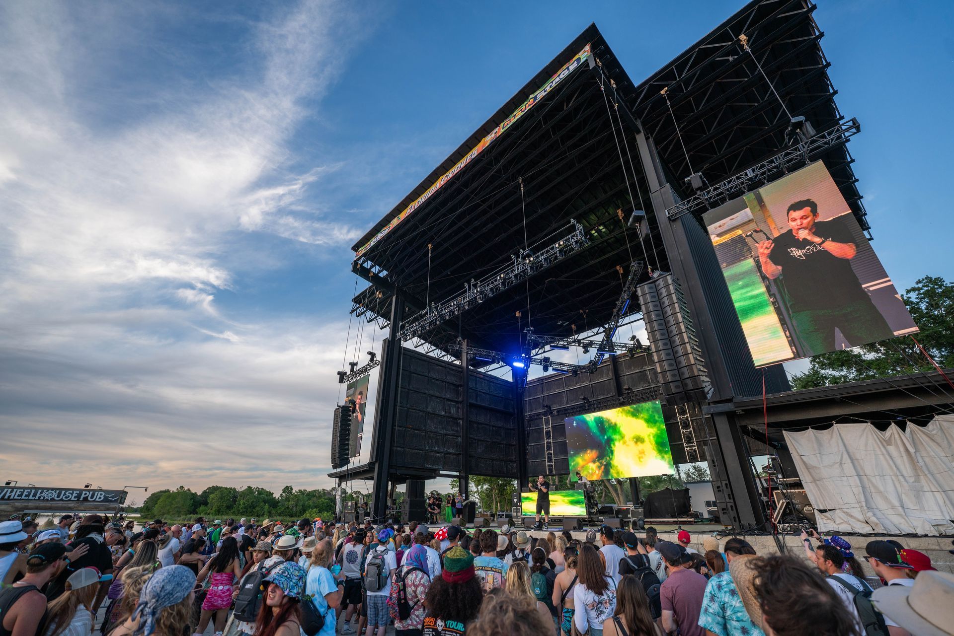 A crowd of people are gathered in front of a large stage at a concert.
