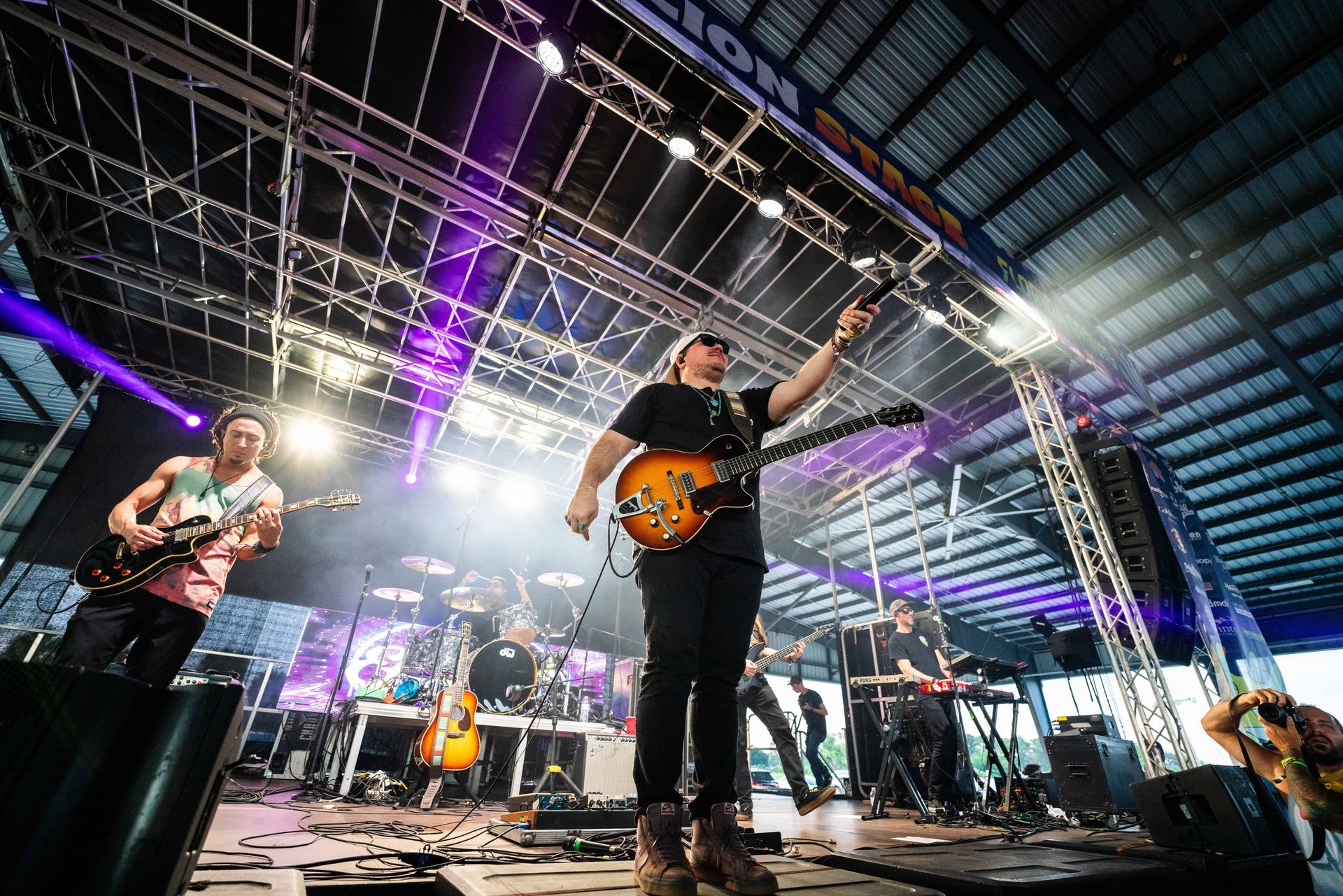 A man is standing on a stage playing a guitar.