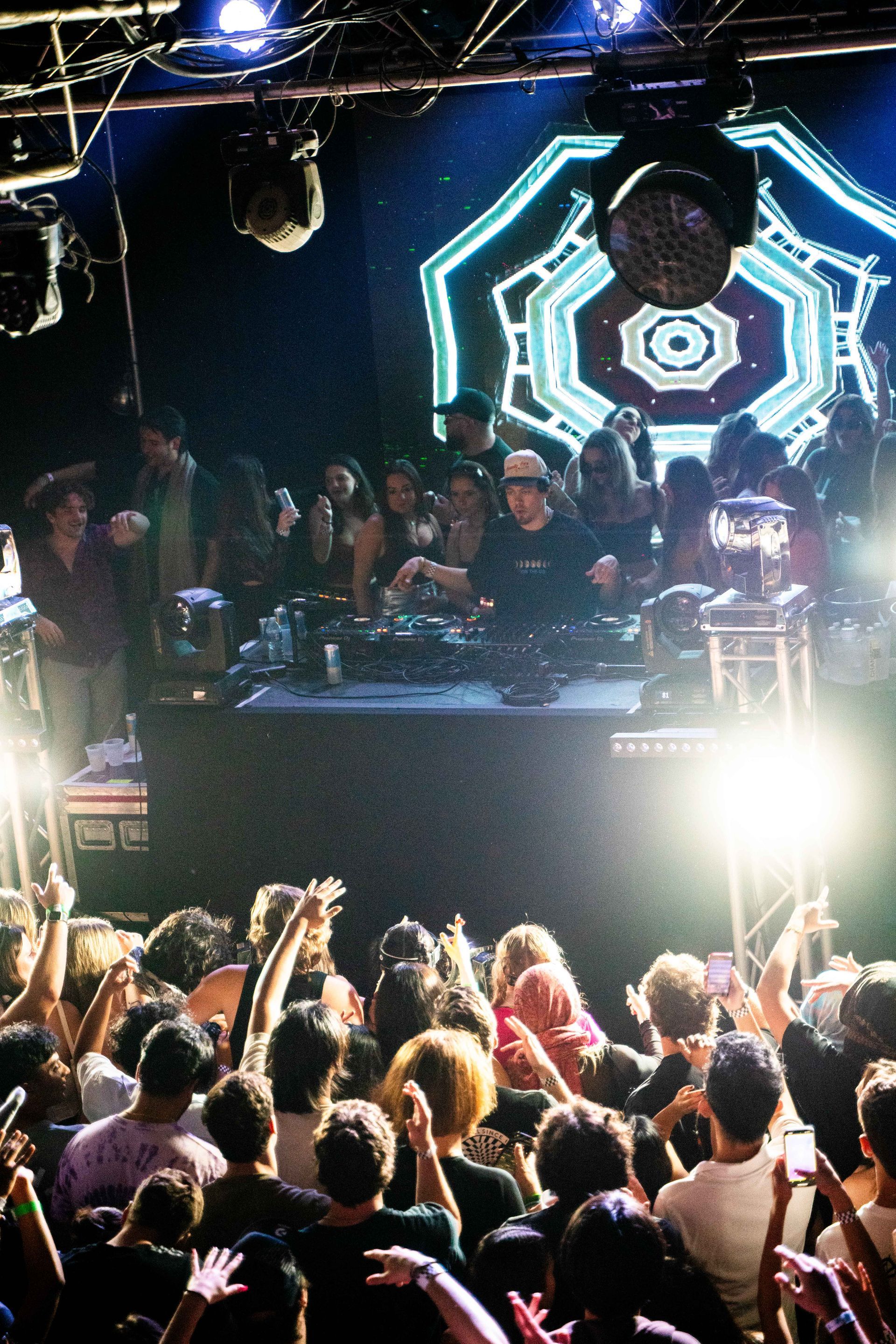 A crowd of people are watching a dj on stage at a concert.
