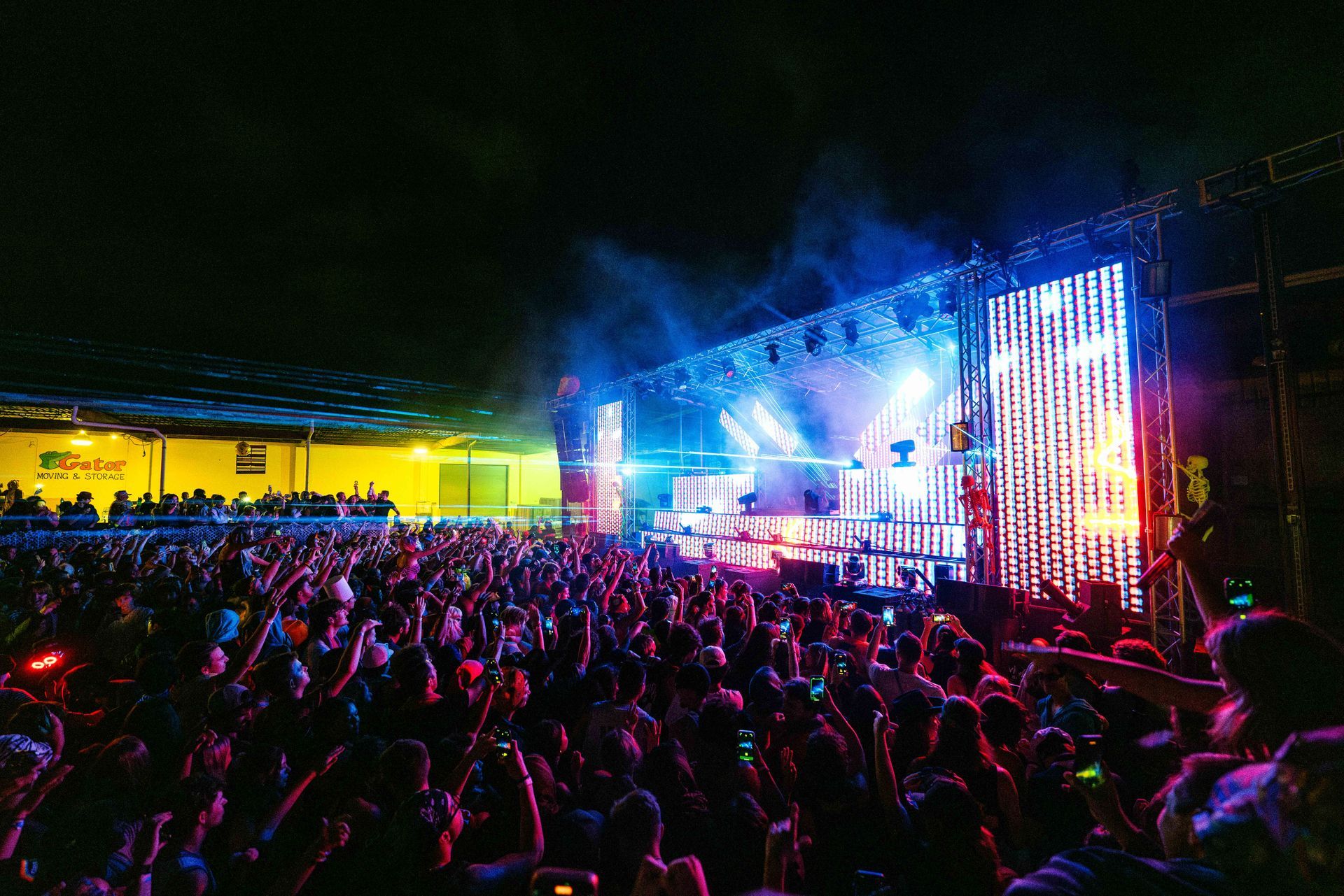 A crowd of people are standing in front of a stage at a concert.