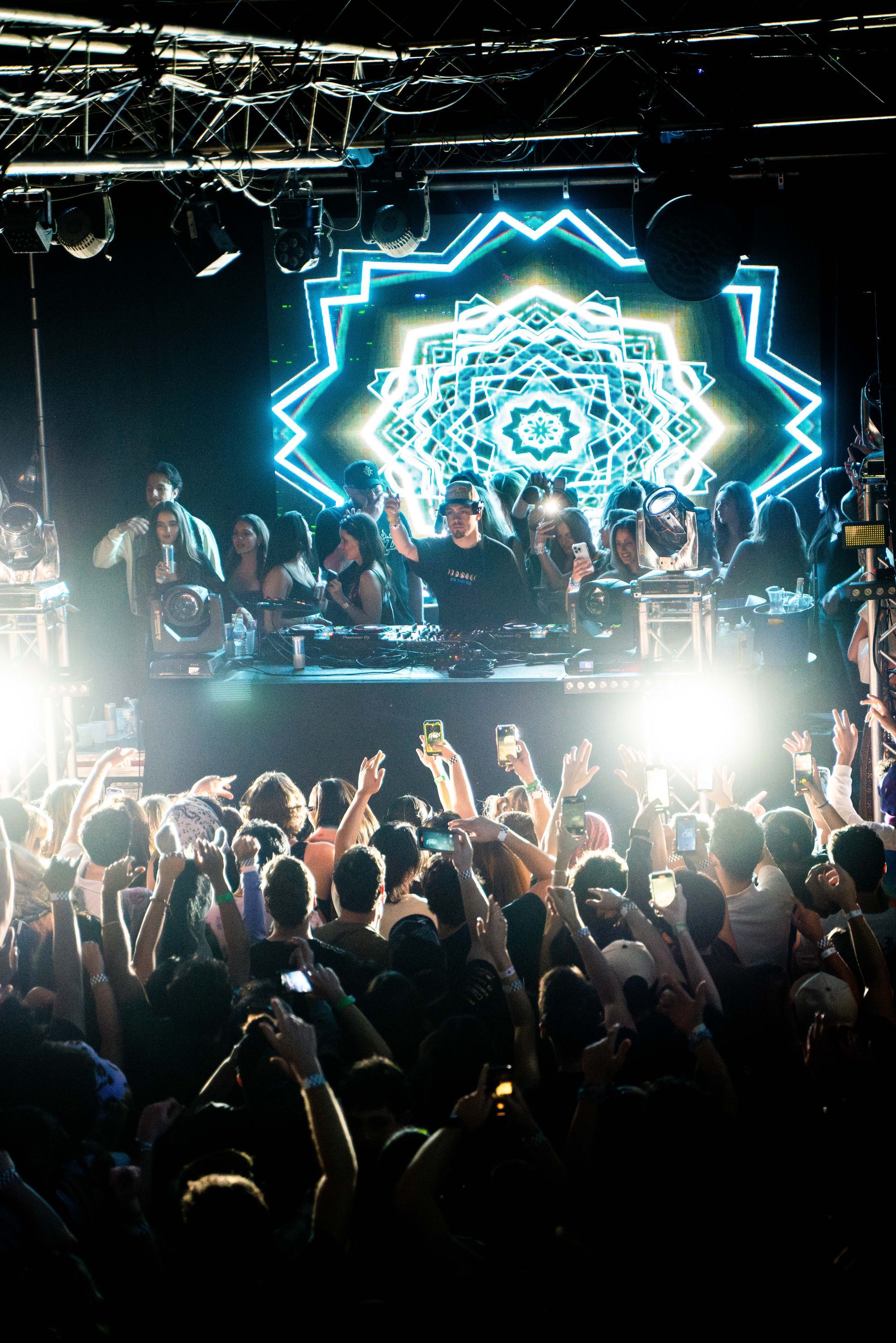 A crowd of people are standing in front of a stage at a concert.
