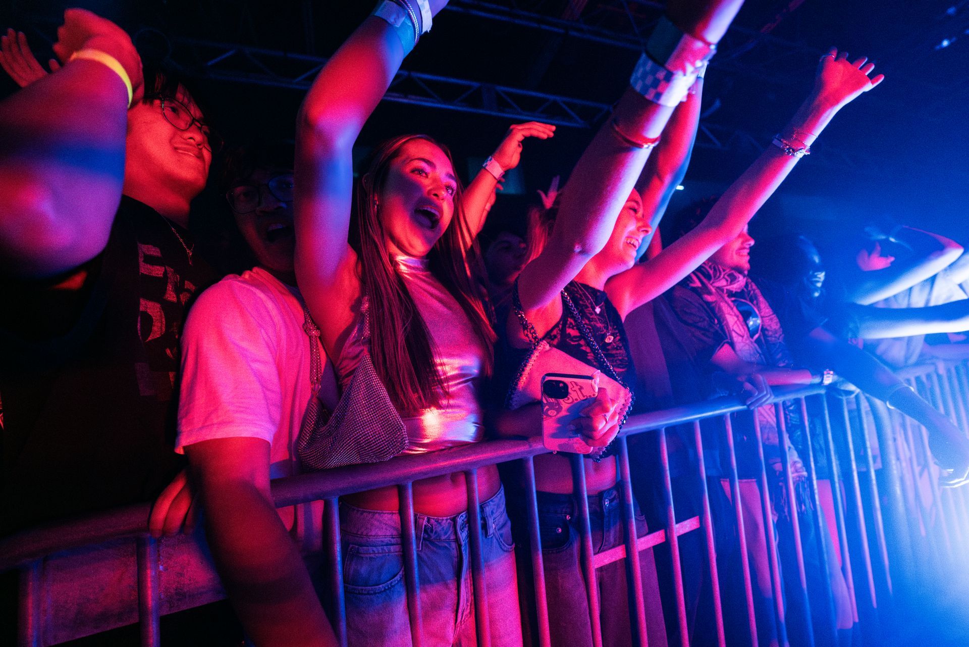 A group of people are standing in a dark room with their arms in the air.