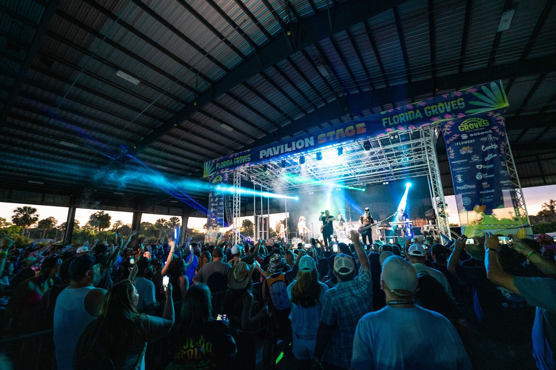 A crowd of people are standing in front of a stage at a concert.