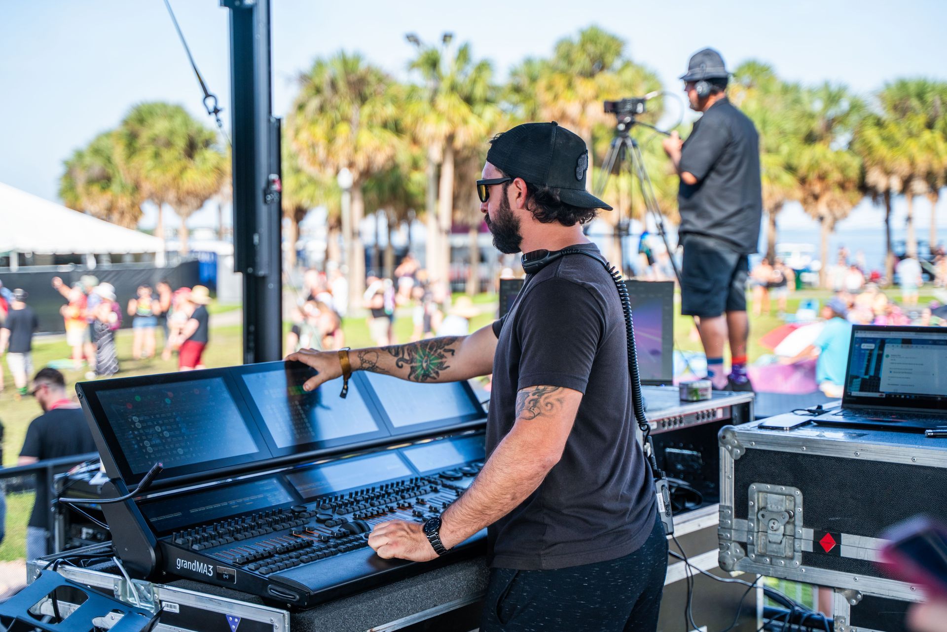 A man is standing in front of a mixer at a concert.
