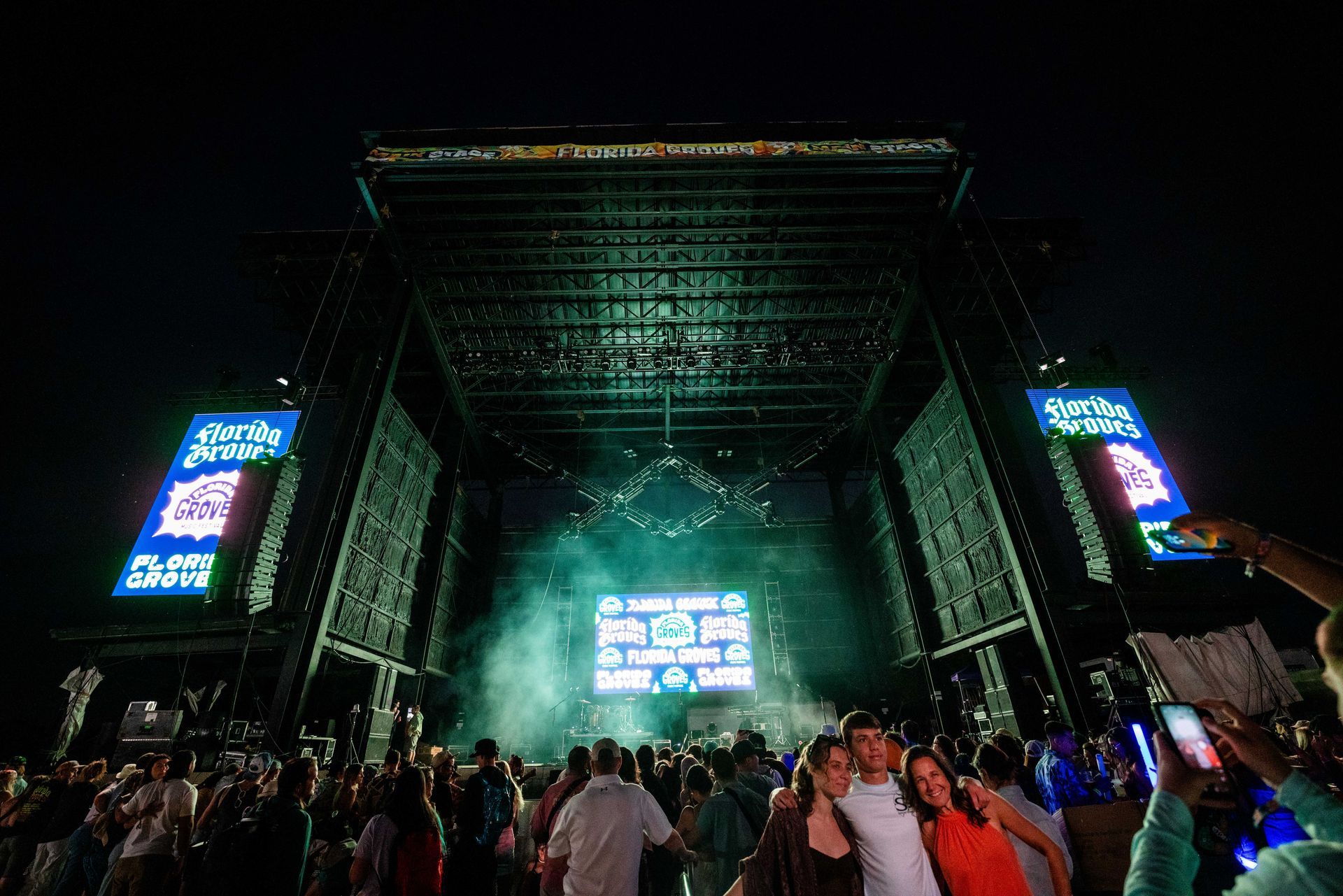 A crowd of people are standing in front of a stage at a concert.