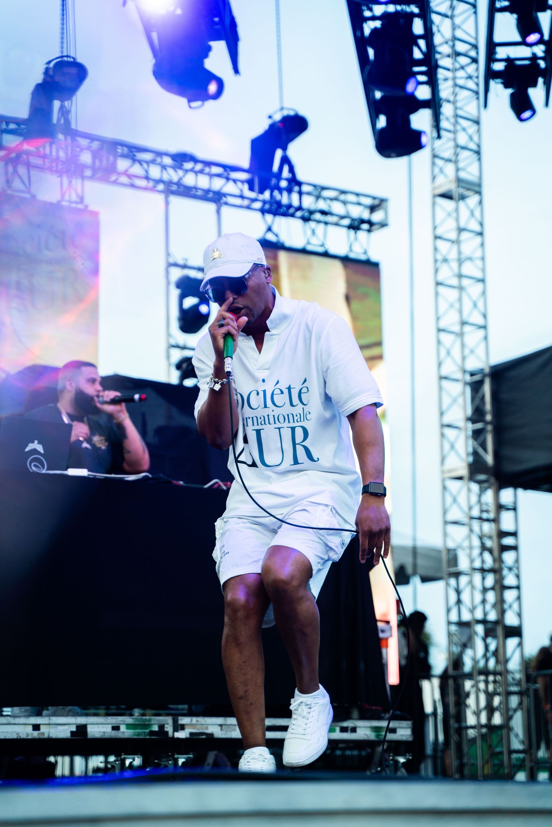 A man is singing into a microphone while wearing a shirt that says ' cielo ' on it