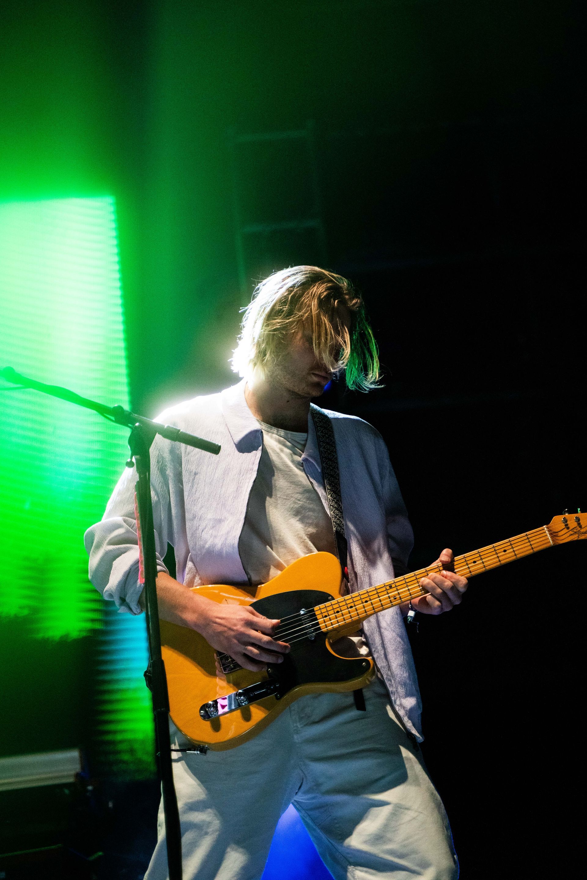 A man is playing a guitar and singing into a microphone on a stage.