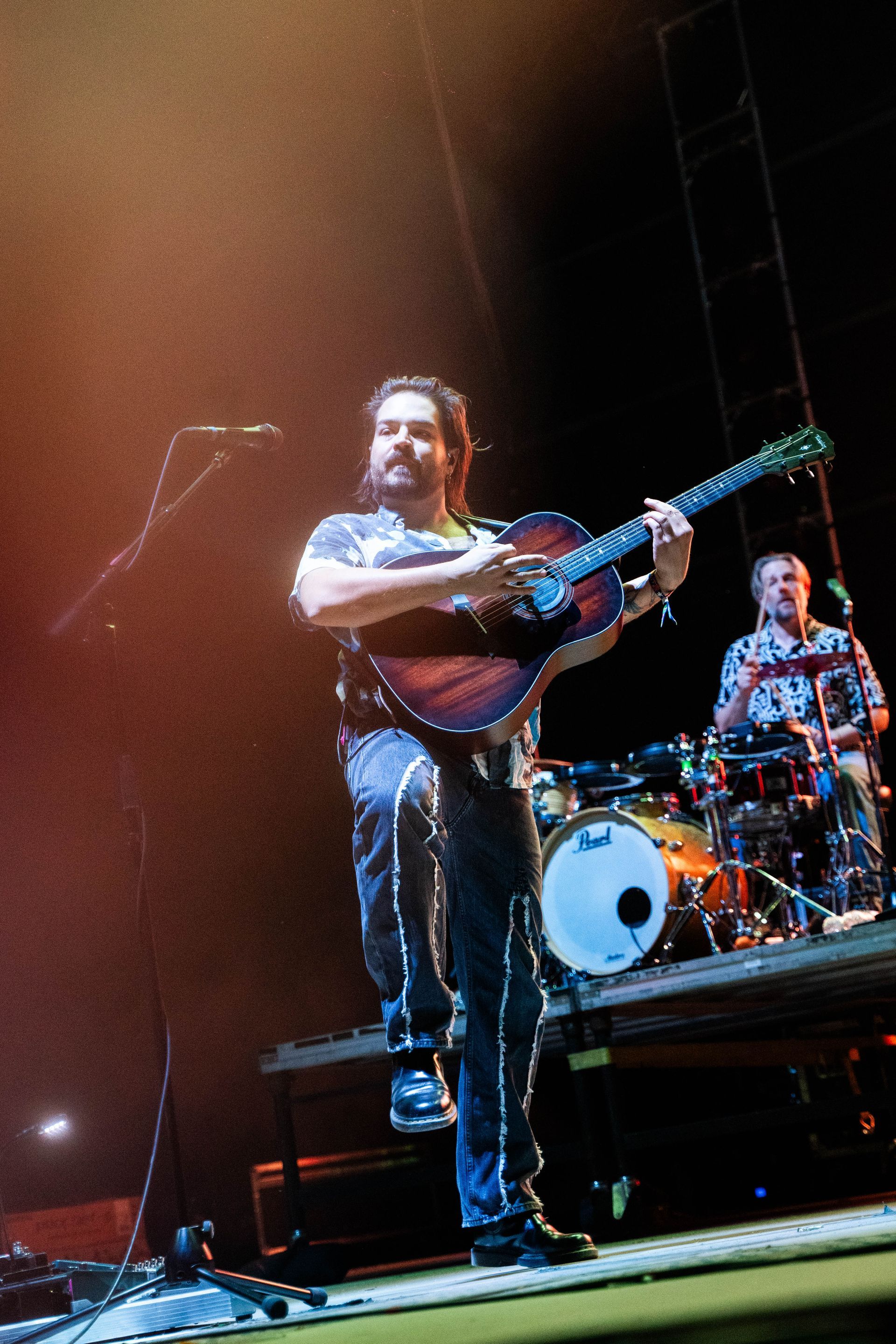 A man is playing a guitar and singing into a microphone on a stage
