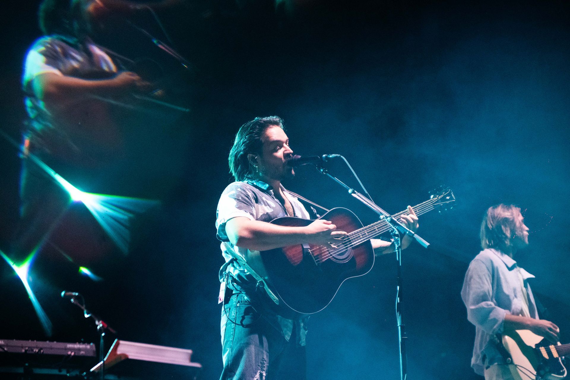 A man singing into a microphone while another man plays a guitar