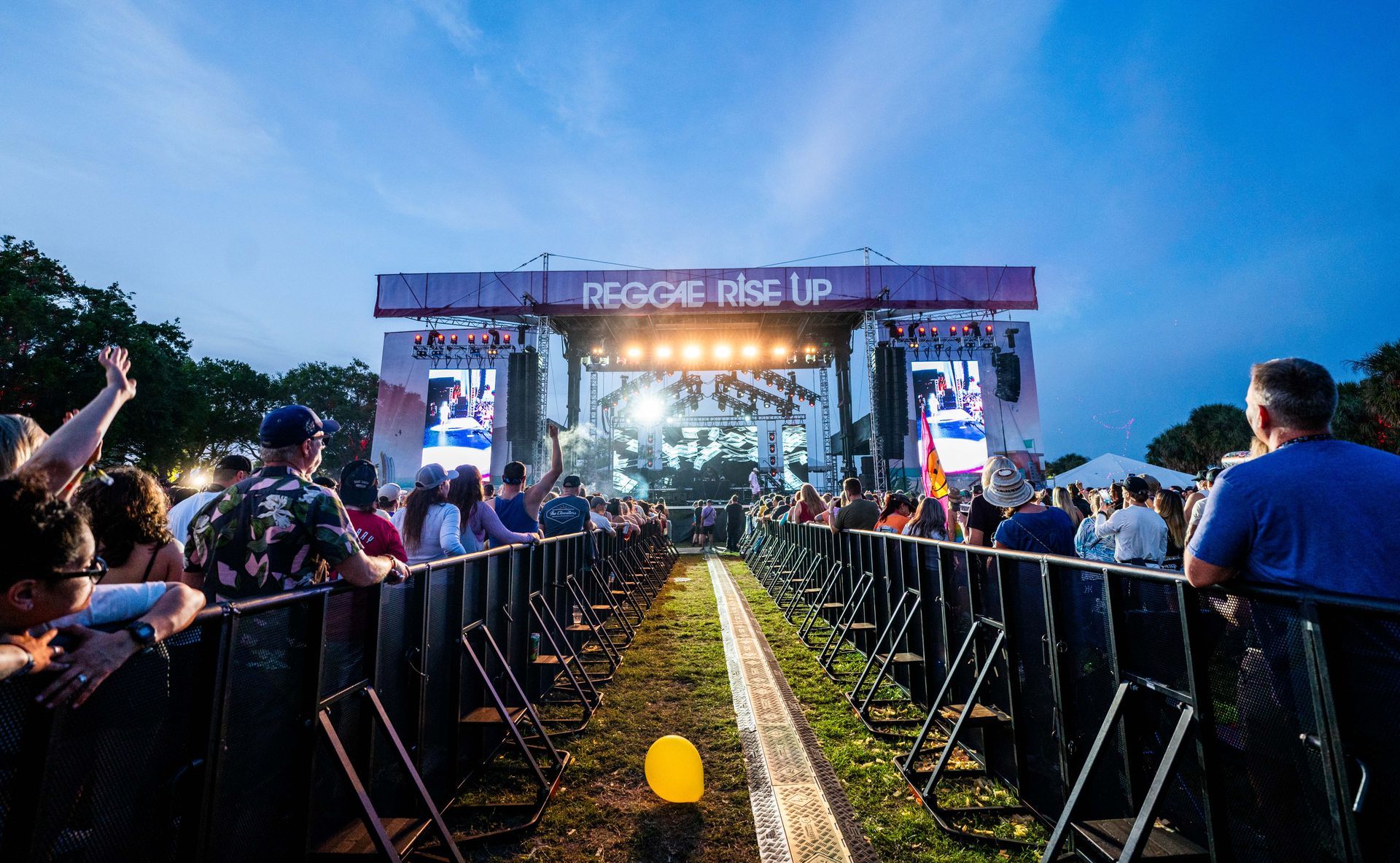 A crowd of people are sitting in front of a stage at a concert.