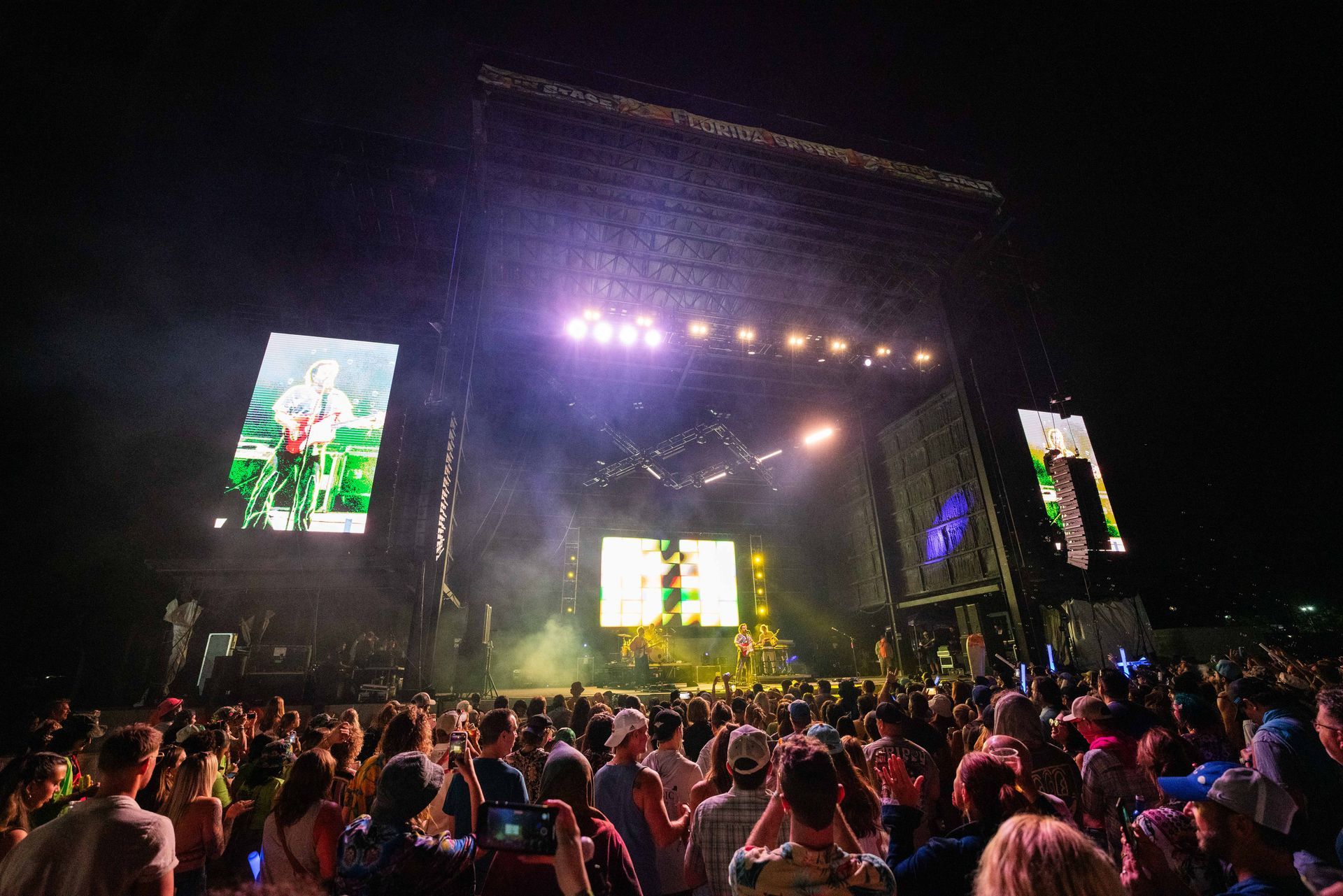 A crowd of people are standing in front of a stage at a concert.