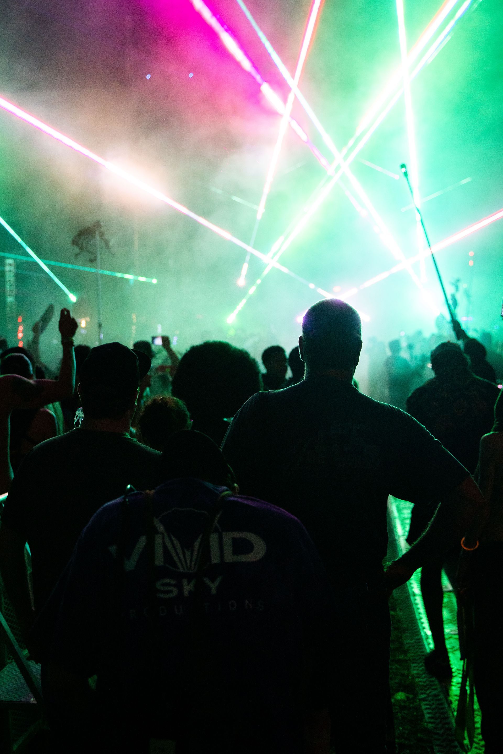 A crowd of people are standing in front of a stage at a concert.