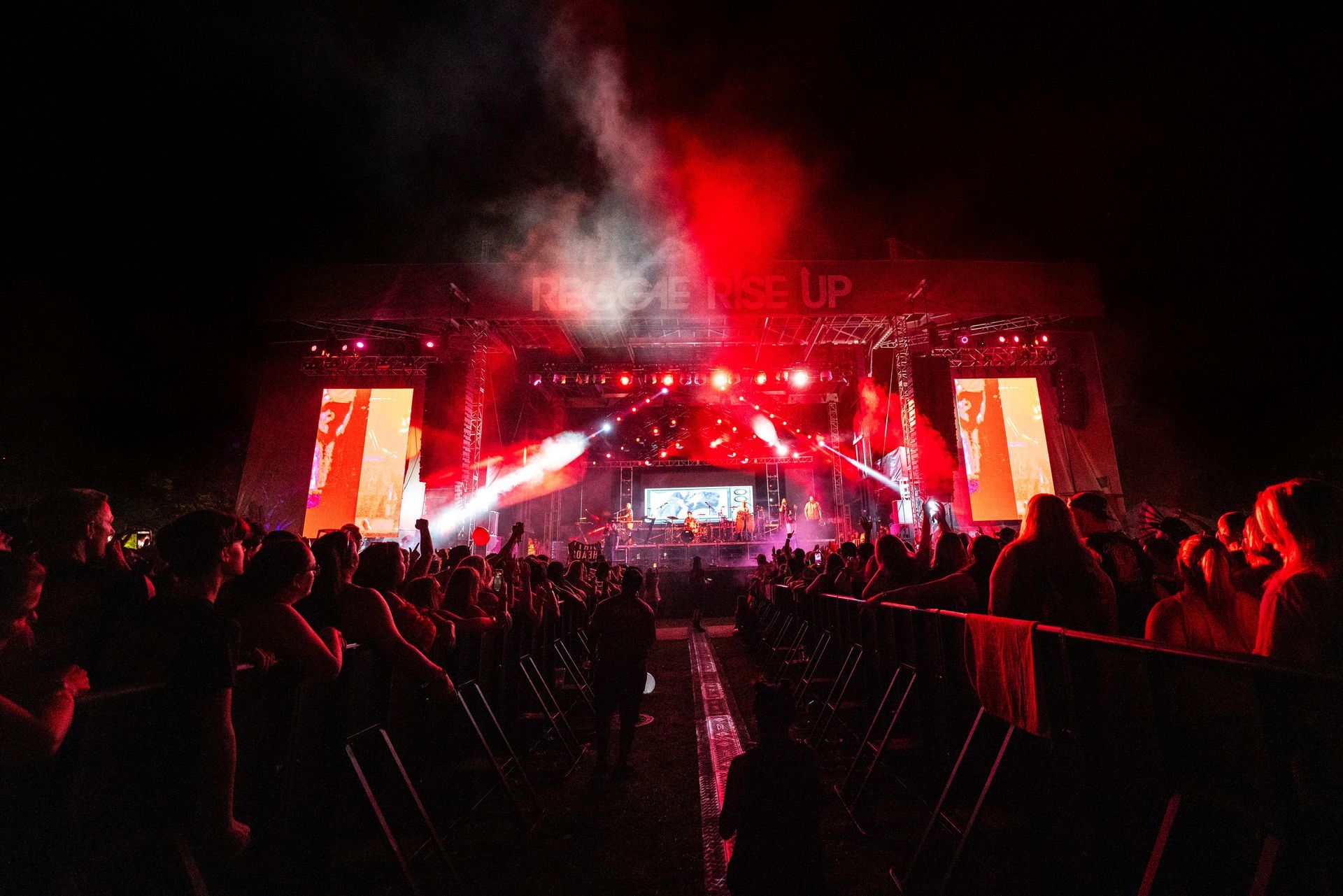 A crowd of people are watching a concert at night.