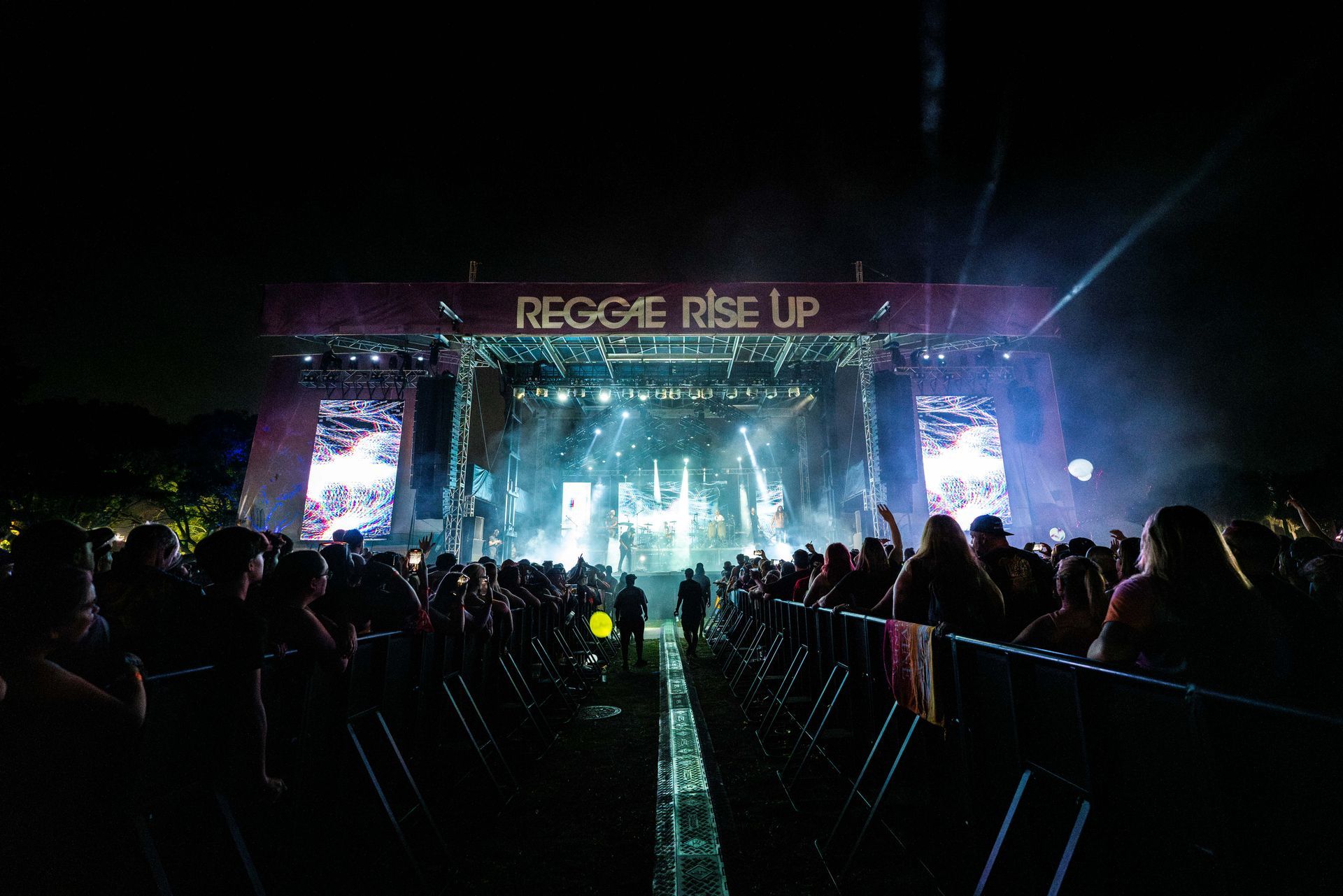 A crowd of people are sitting in front of a stage at a concert.
