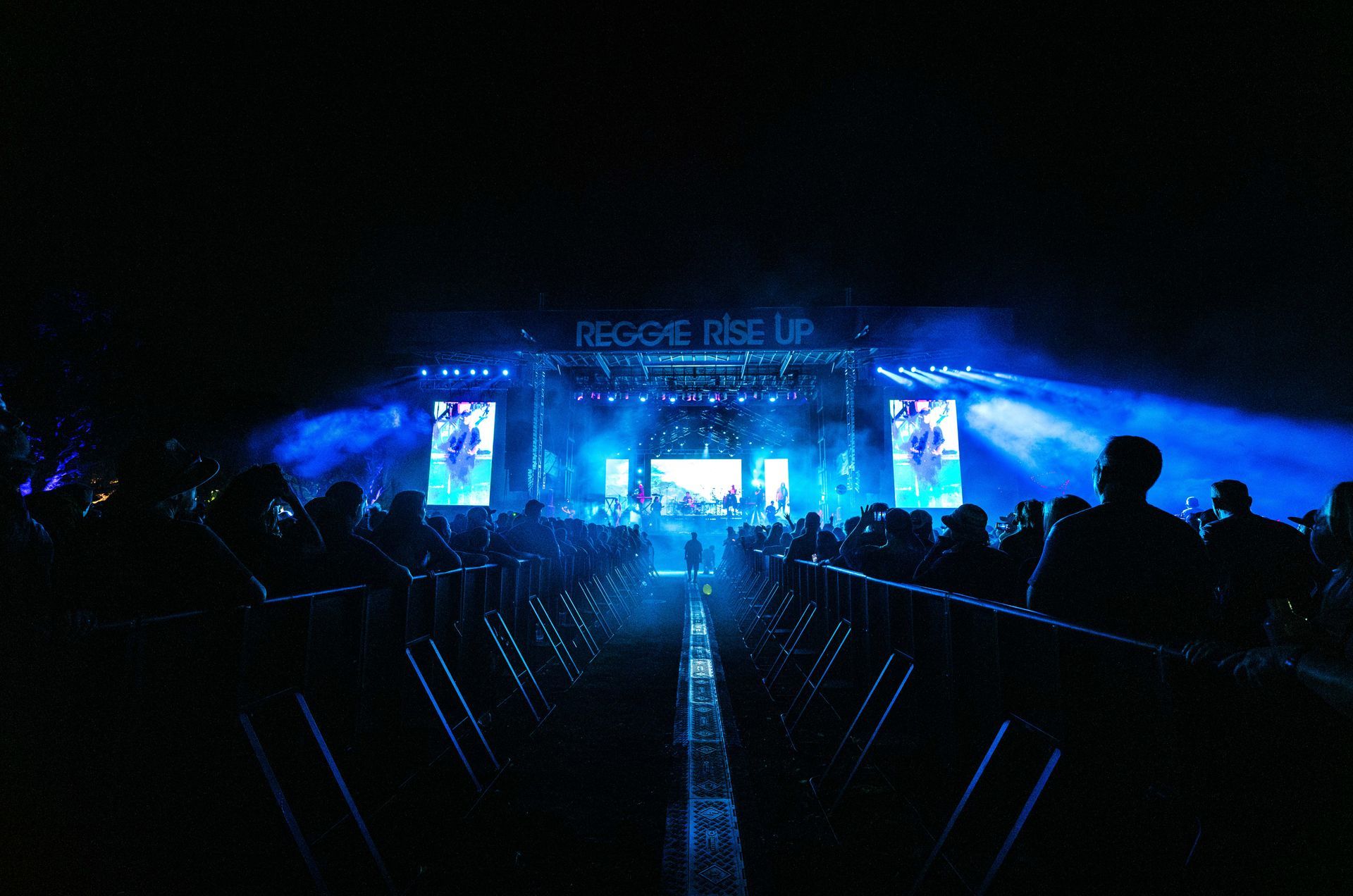 A crowd of people are watching a concert at night