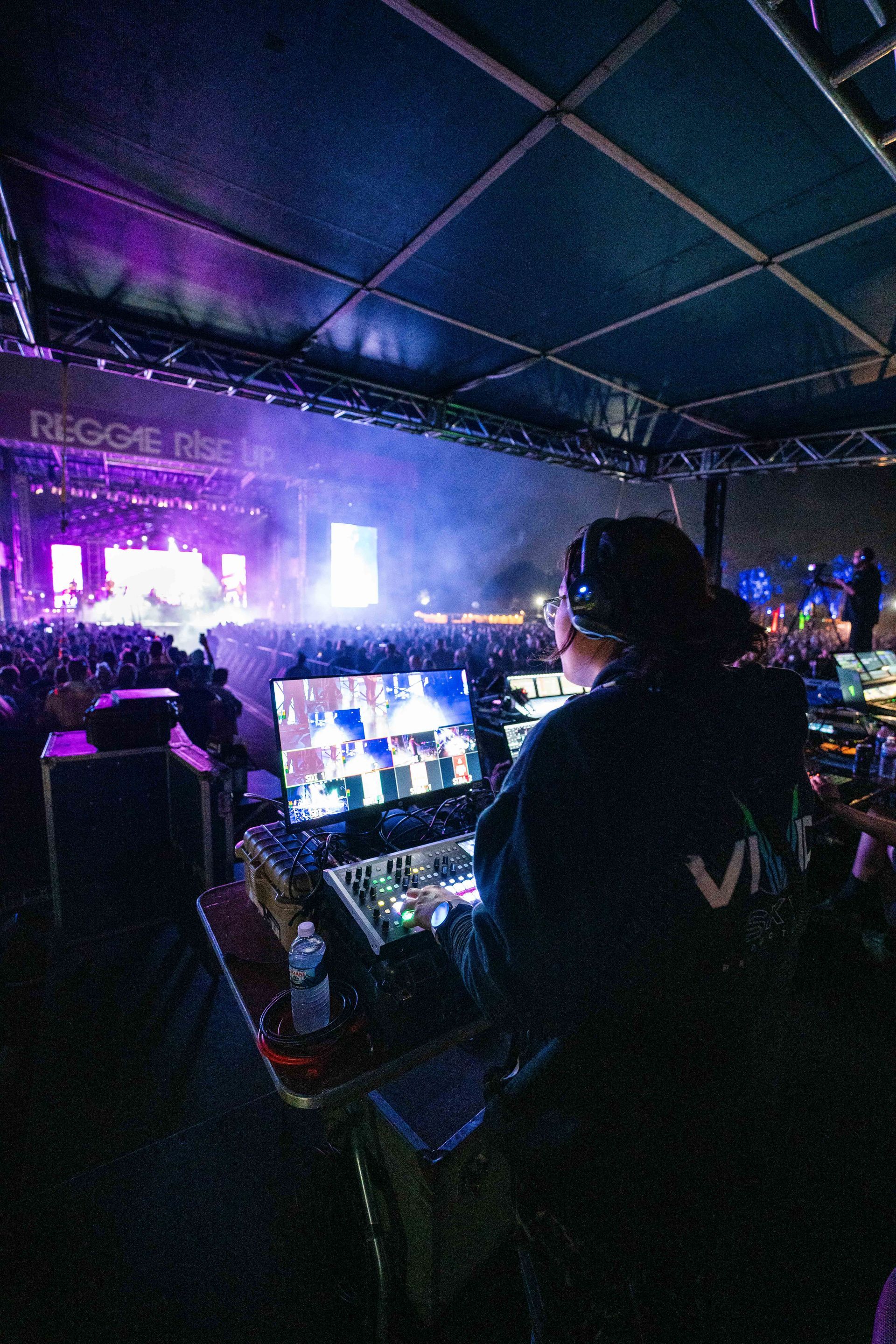 A man is sitting at a desk in front of a crowd at a concert.