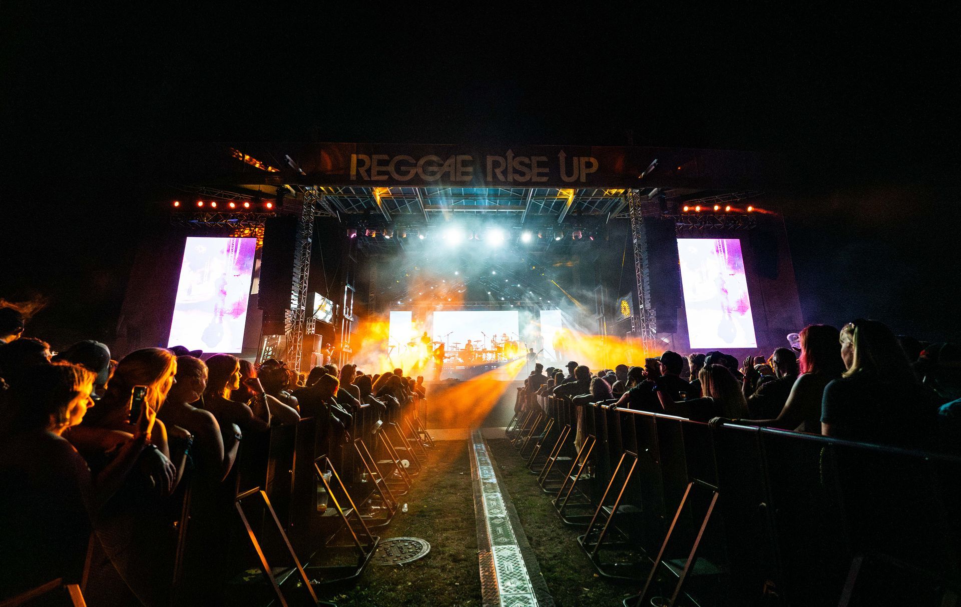 A crowd of people watching a concert with a sign that says reggae rise up