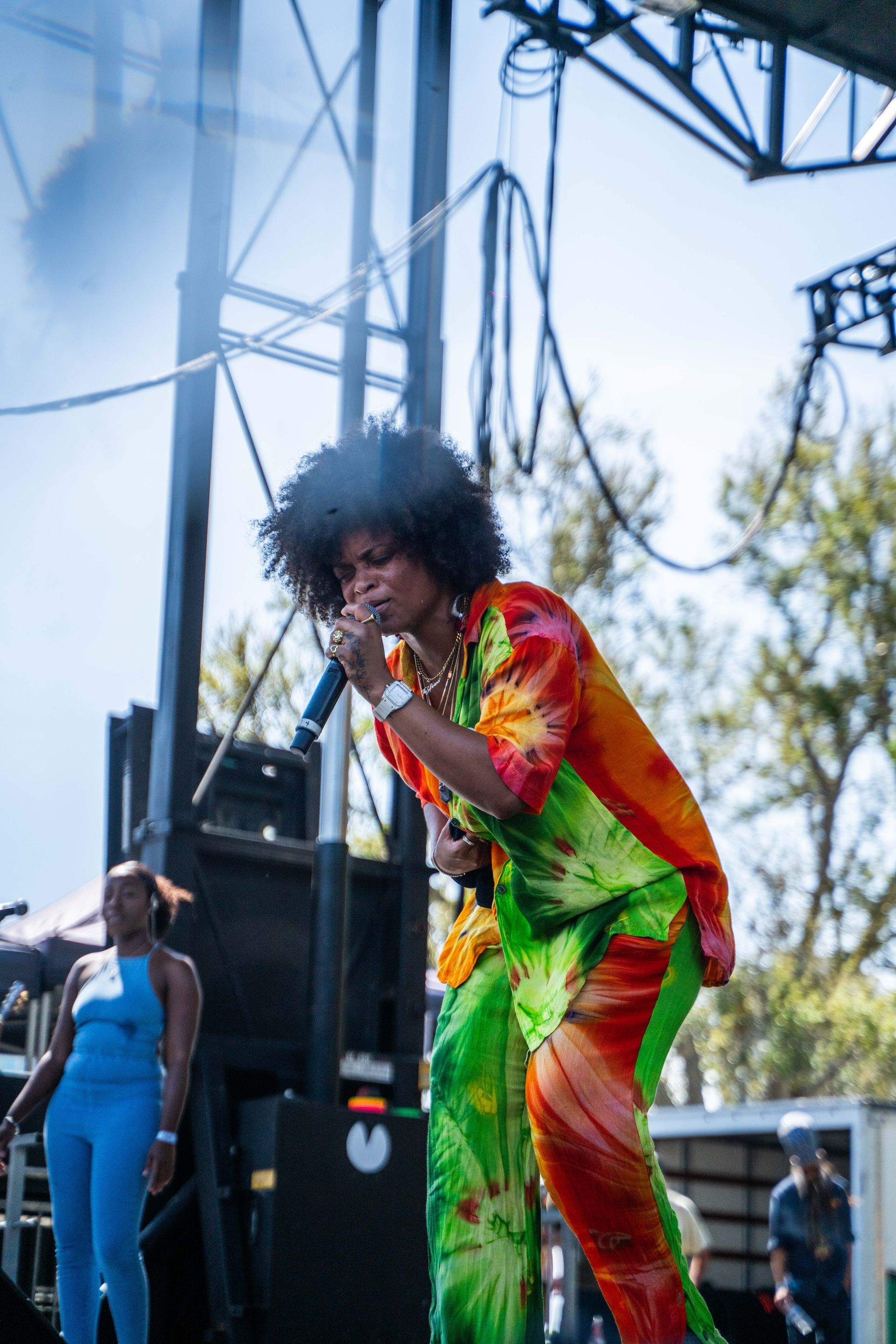 A man in a colorful outfit is singing into a microphone on a stage.