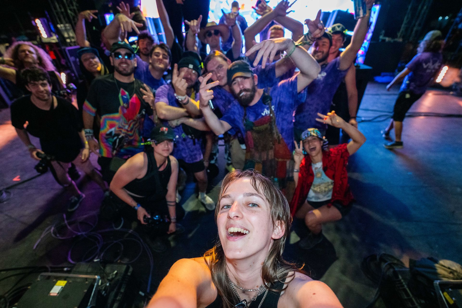 A woman is taking a selfie with a group of people at a concert.