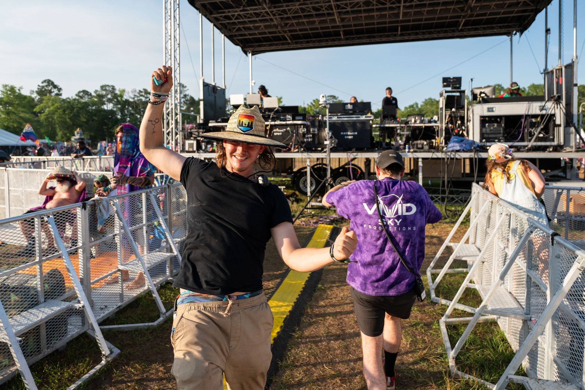 A group of people are dancing in front of a stage at a music festival.