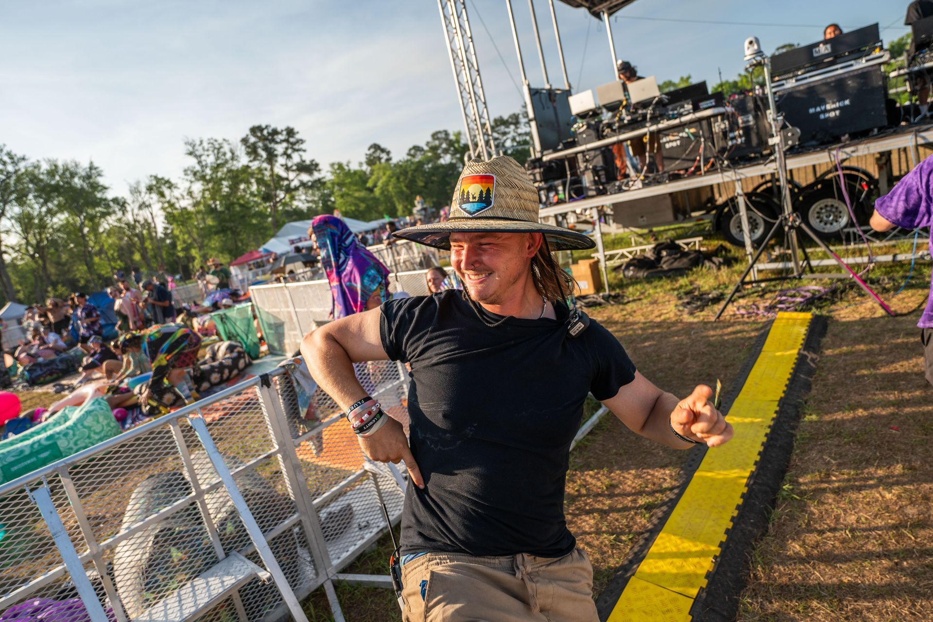 A man wearing a cowboy hat is dancing in front of a crowd at a music festival.