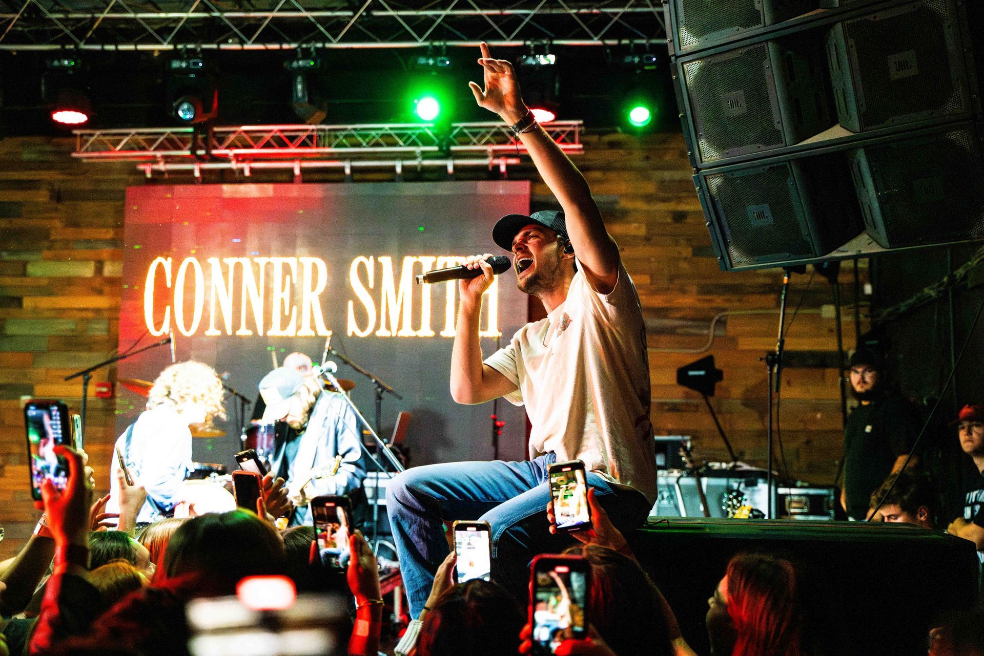 A man is singing into a microphone on a stage in front of a crowd.