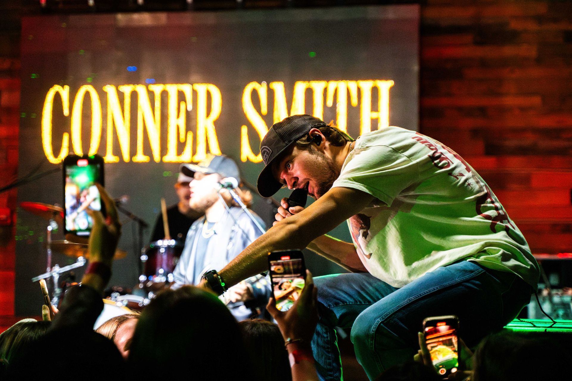 A man is singing into a microphone on stage in front of a crowd.