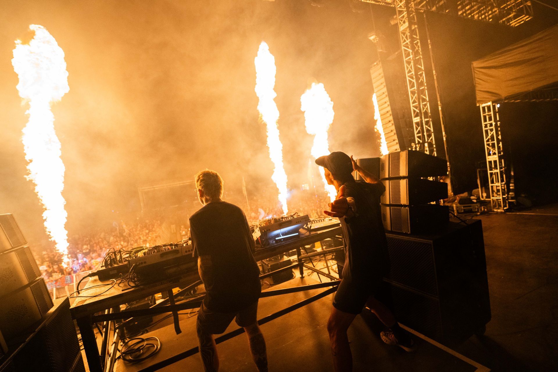 Two men are standing on a stage with flames coming out of the ceiling.