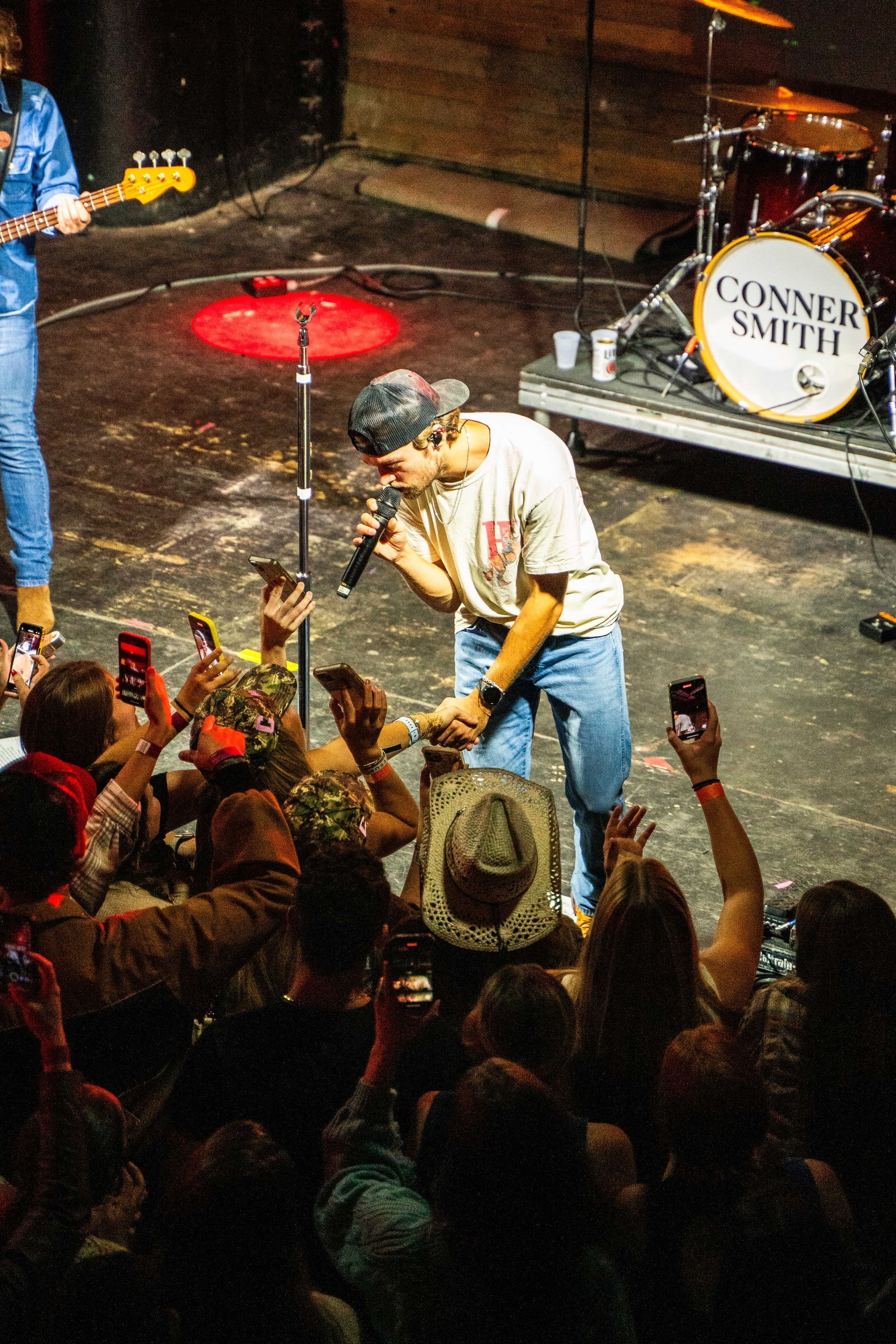 A man is singing into a microphone on a stage in front of a crowd.