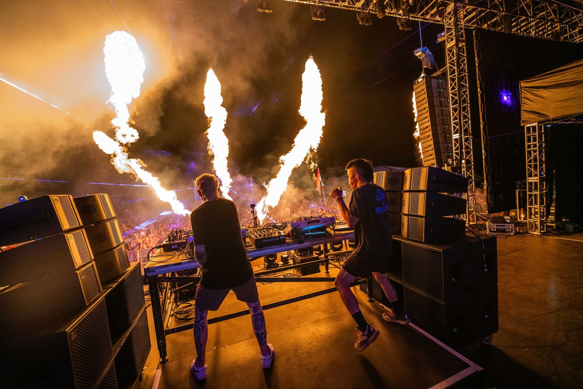 Two men are playing music on a stage with fireworks in the background.
