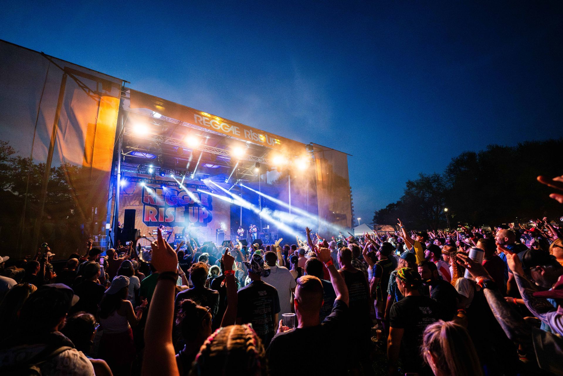 A crowd of people are standing in front of a stage at a concert.