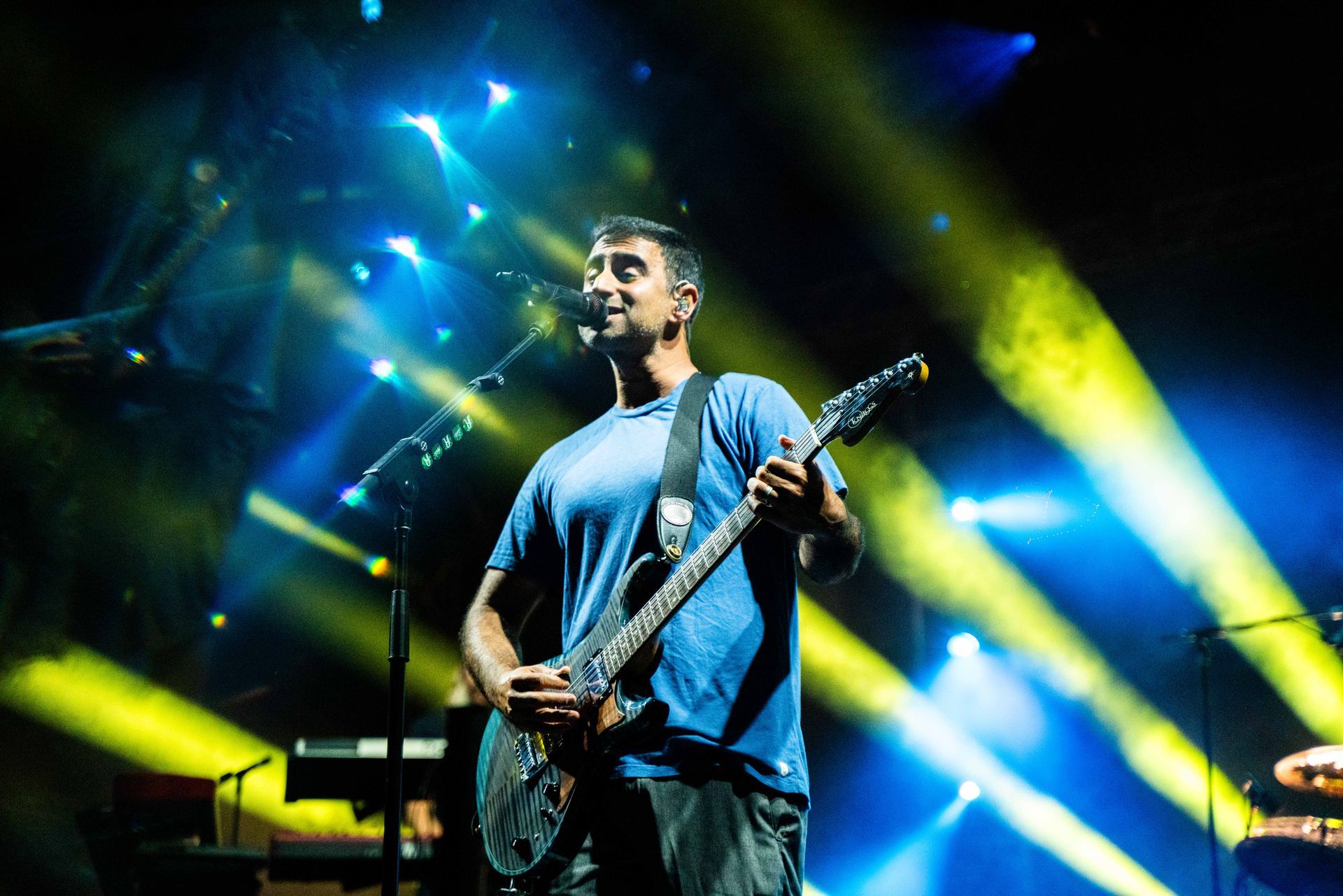 A man is playing a guitar and singing into a microphone on a stage.