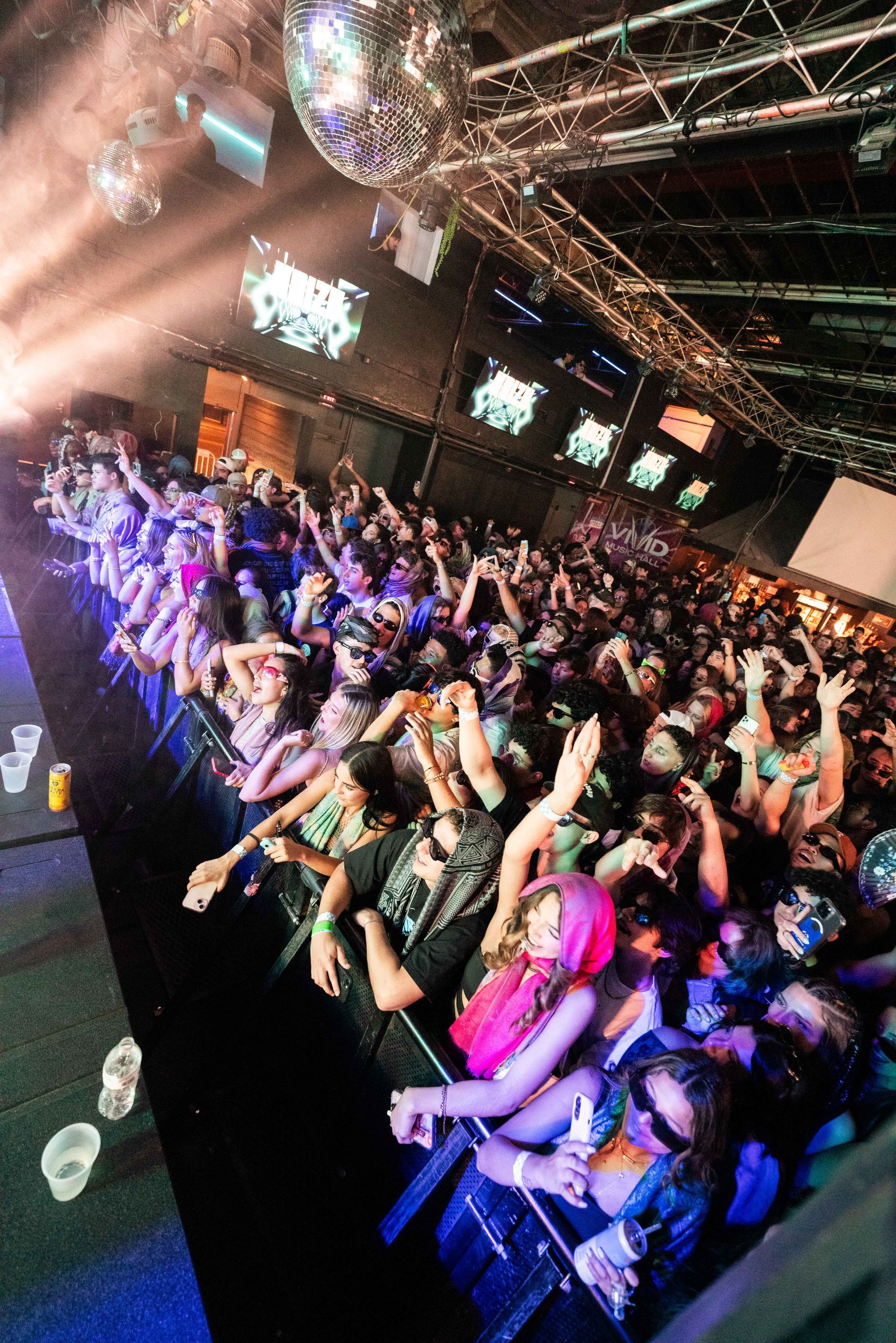 A crowd of people are standing in front of a stage at a concert.