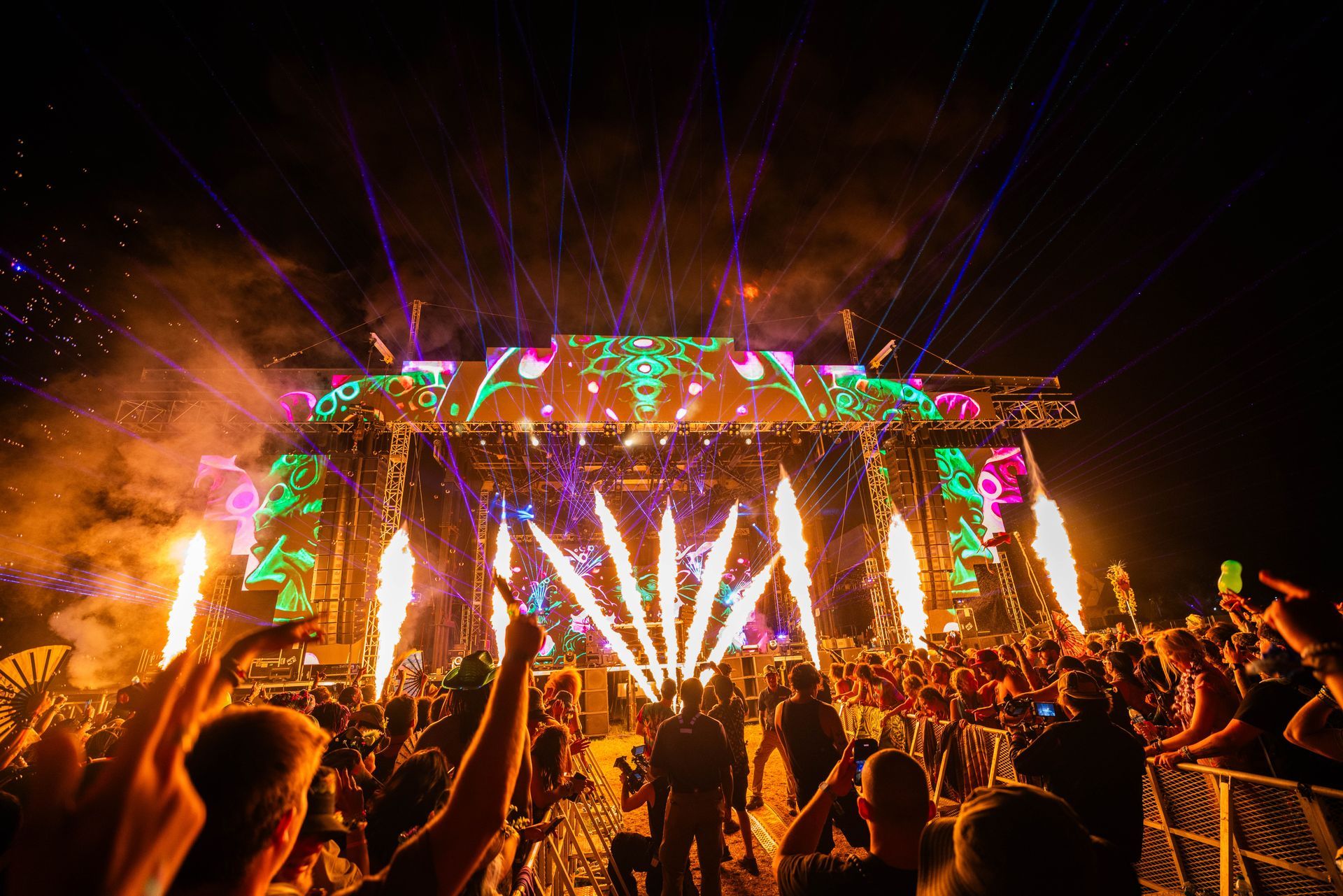 A crowd of people are standing in front of a stage at a concert.