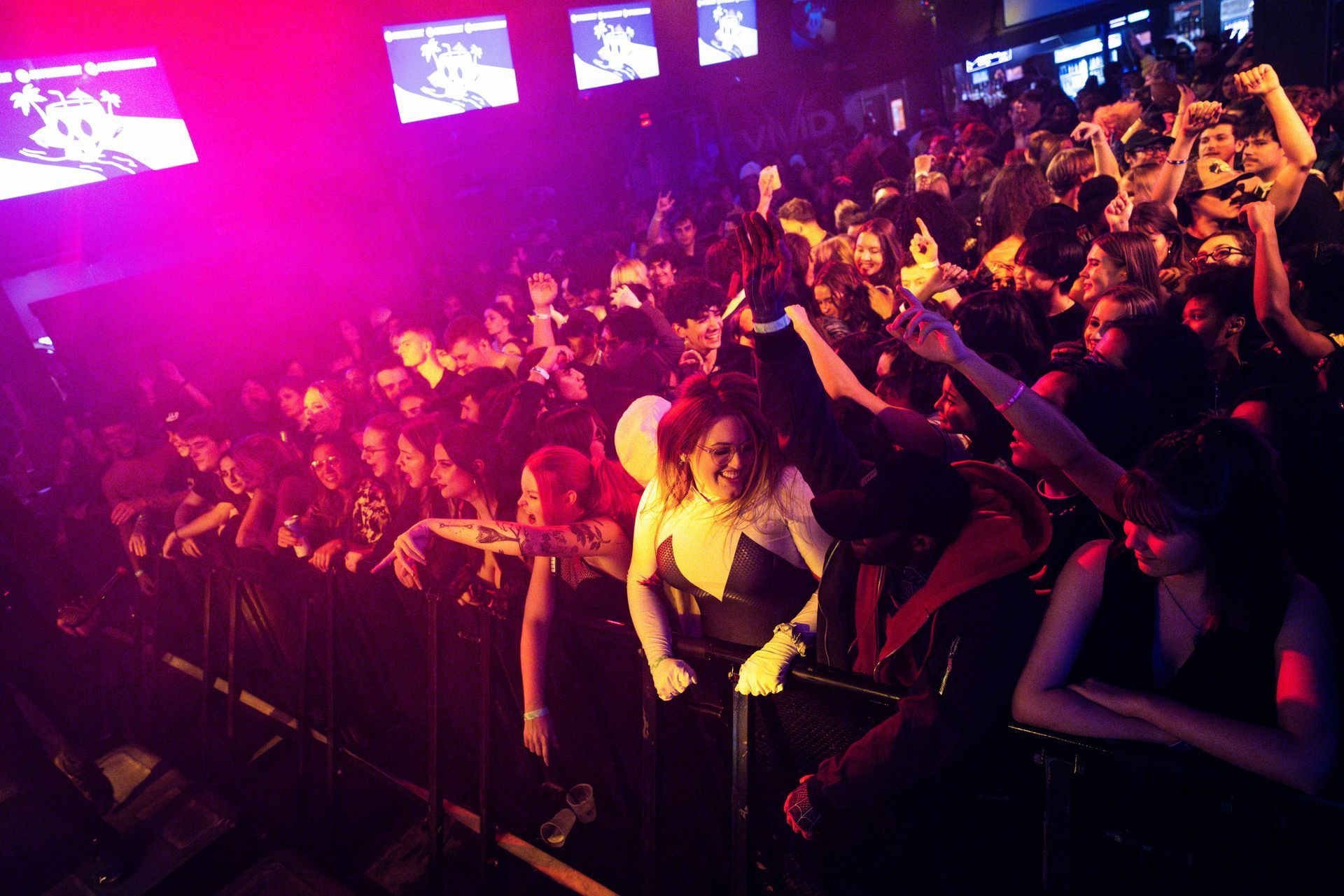 A crowd of people are standing in front of a stage at a concert.