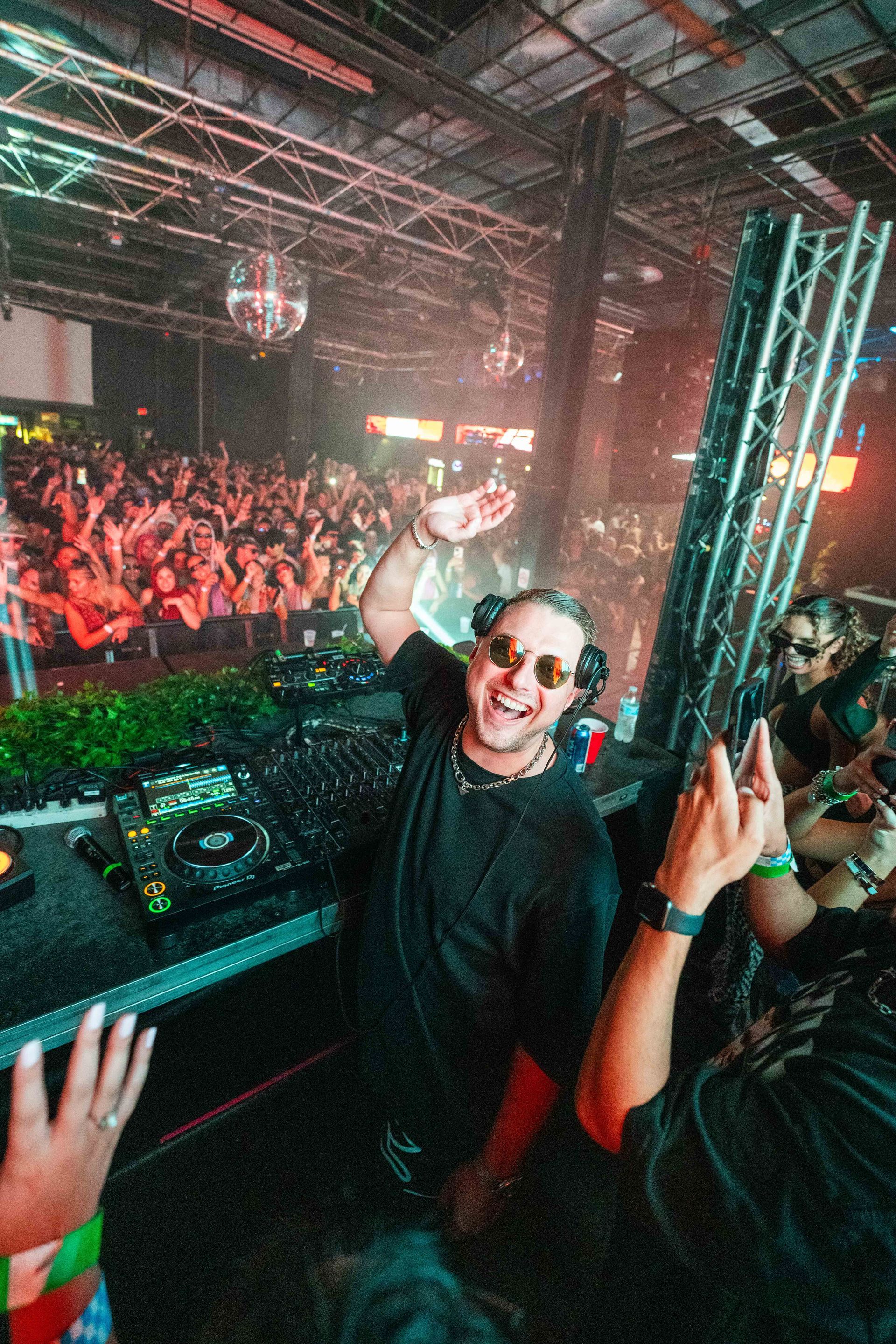 A dj is playing music in front of a crowd at a concert.