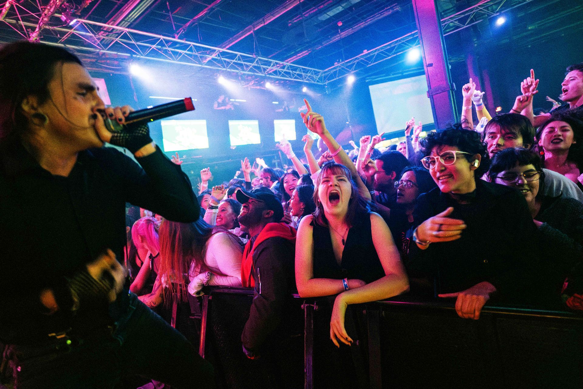 A man is singing into a microphone in front of a crowd at a concert.