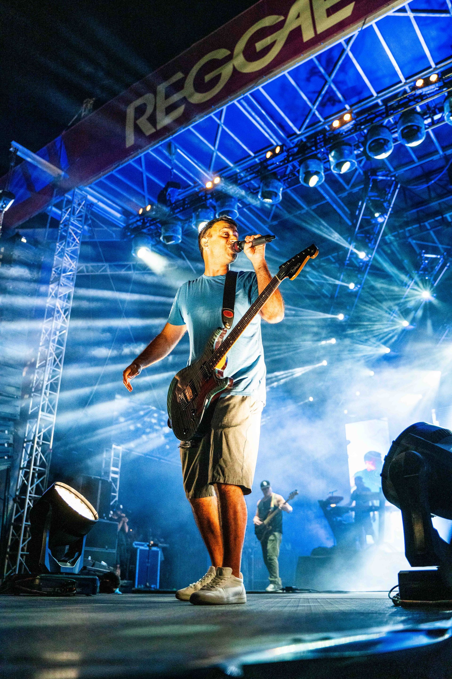 A man is singing into a microphone while playing a guitar on stage.